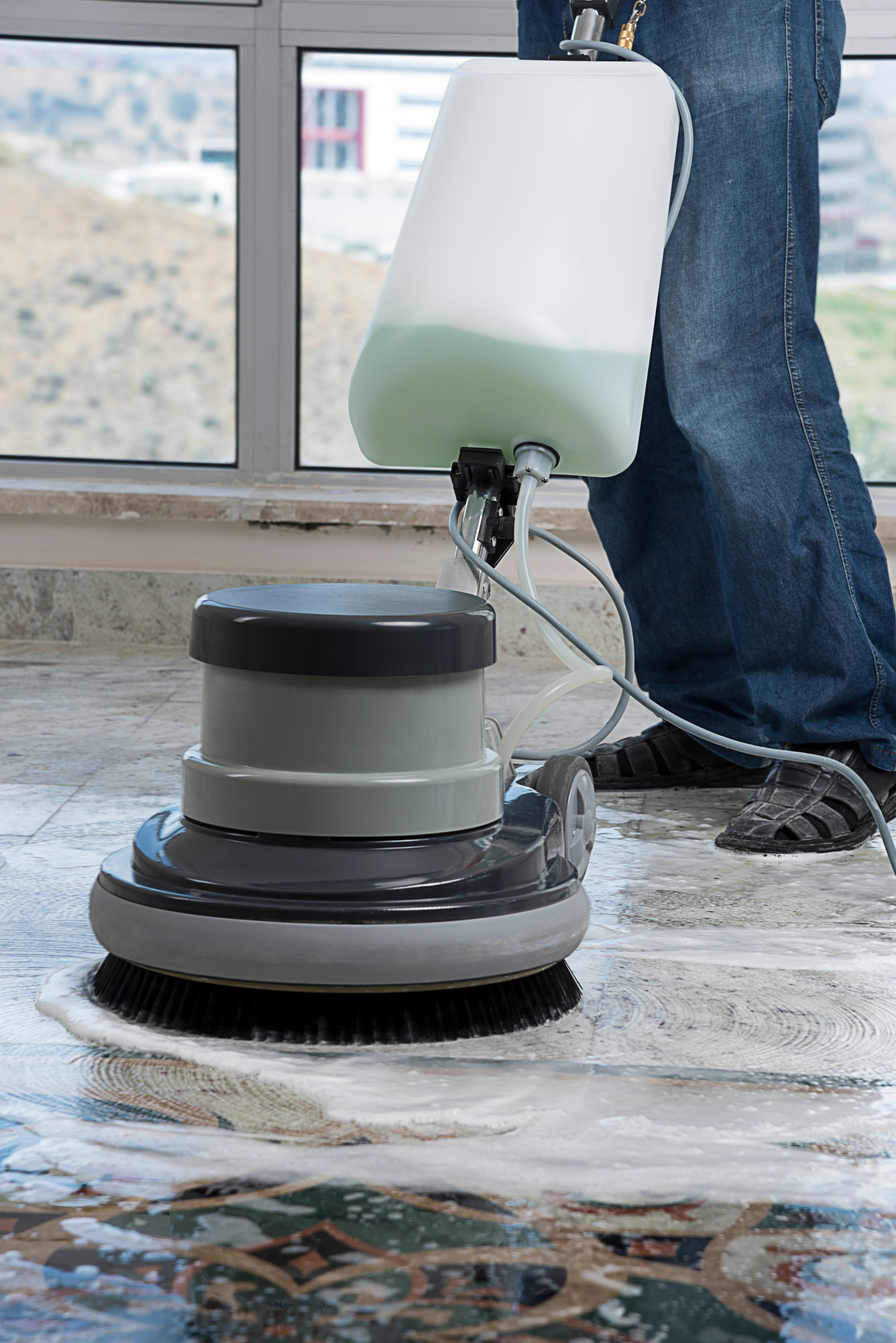 A person is cleaning a tile floor with a machine.