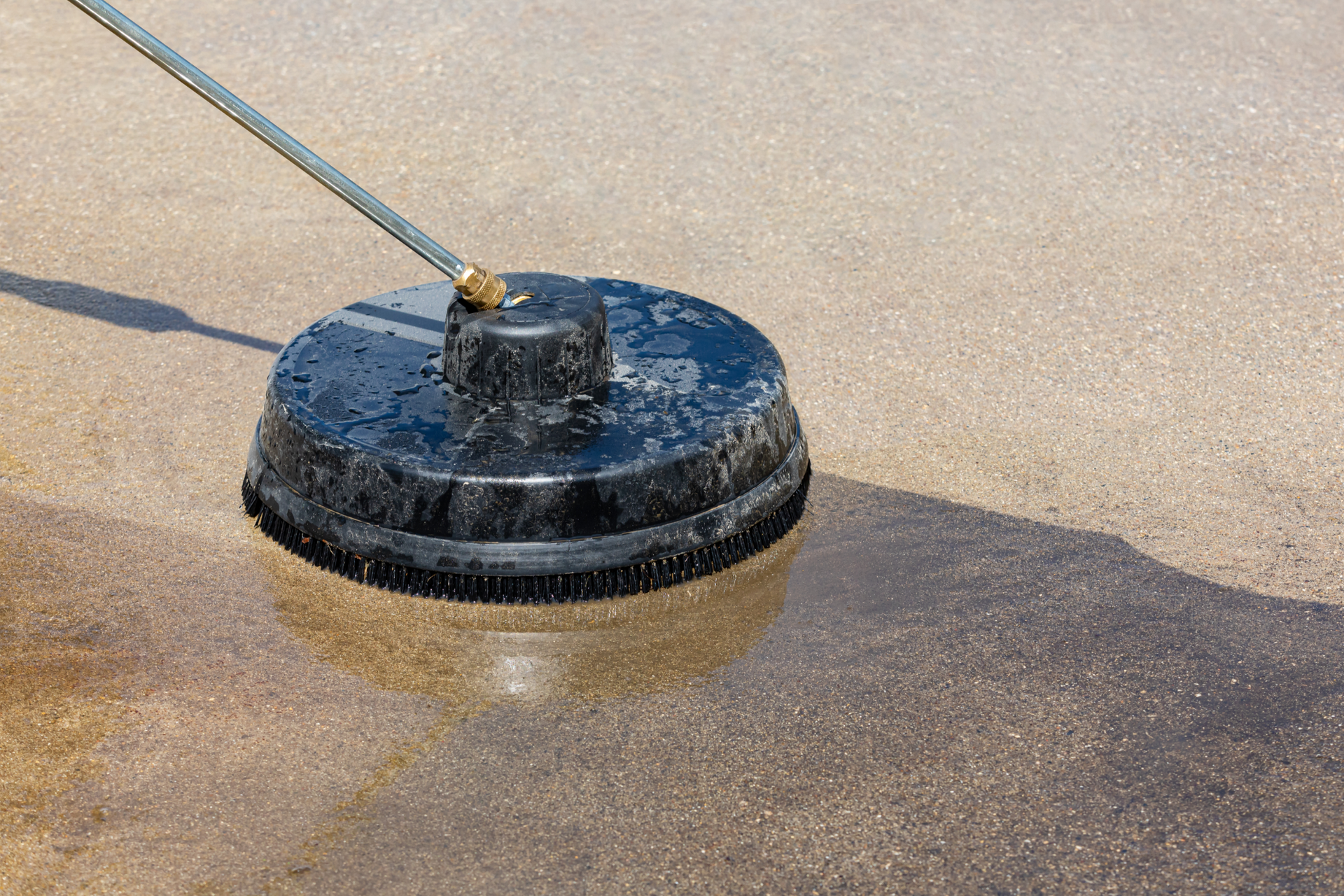 A person is using a pressure washer to clean a concrete floor.