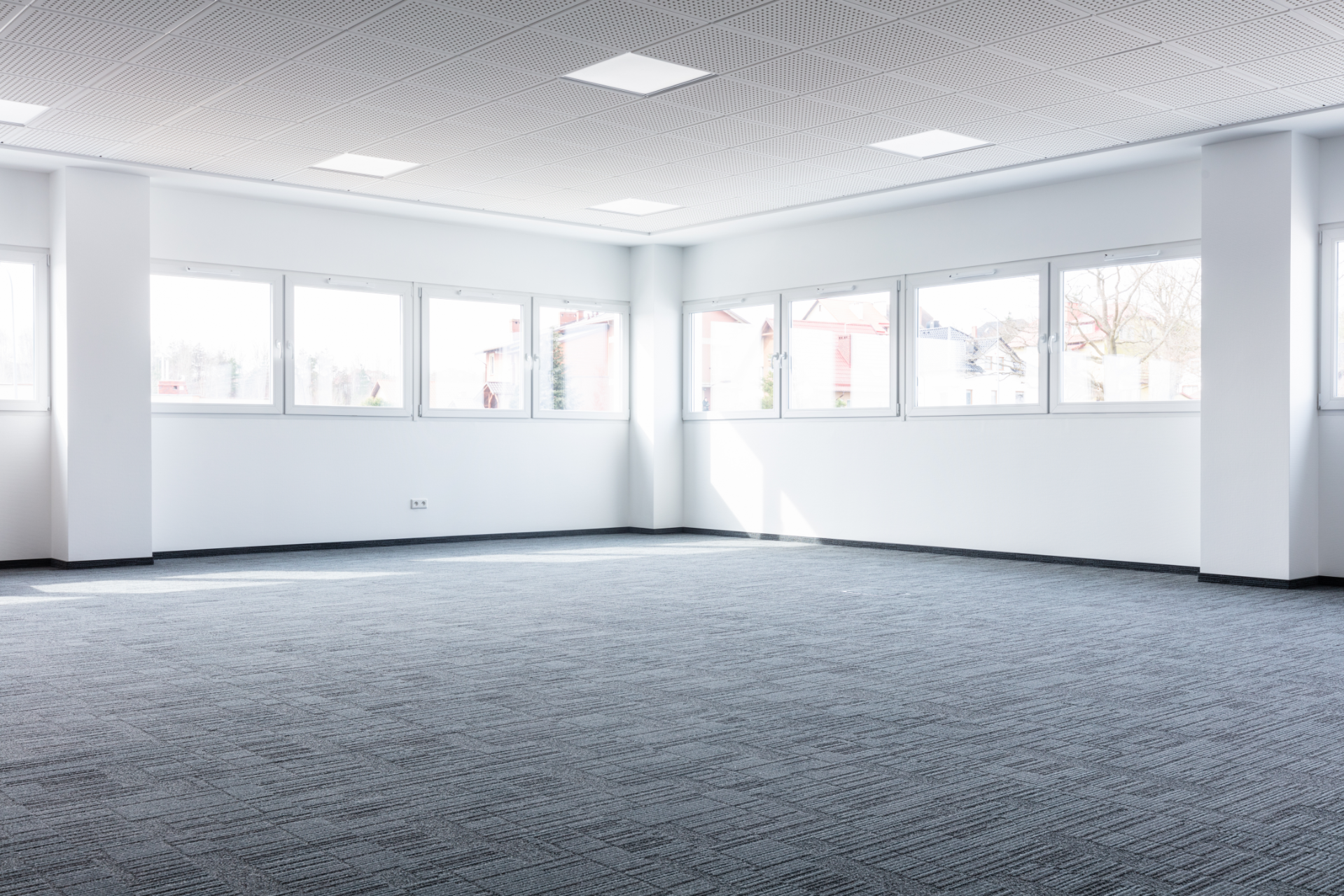 An empty room with a lot of windows and a carpeted floor.