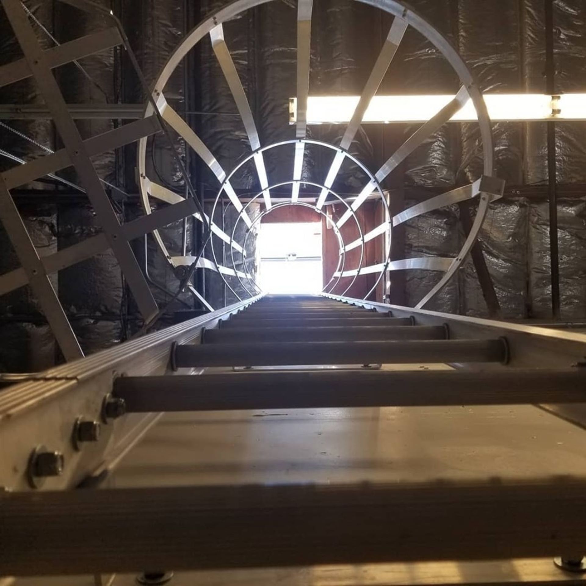 Ladder ascending towards bright doorway, inside a building.