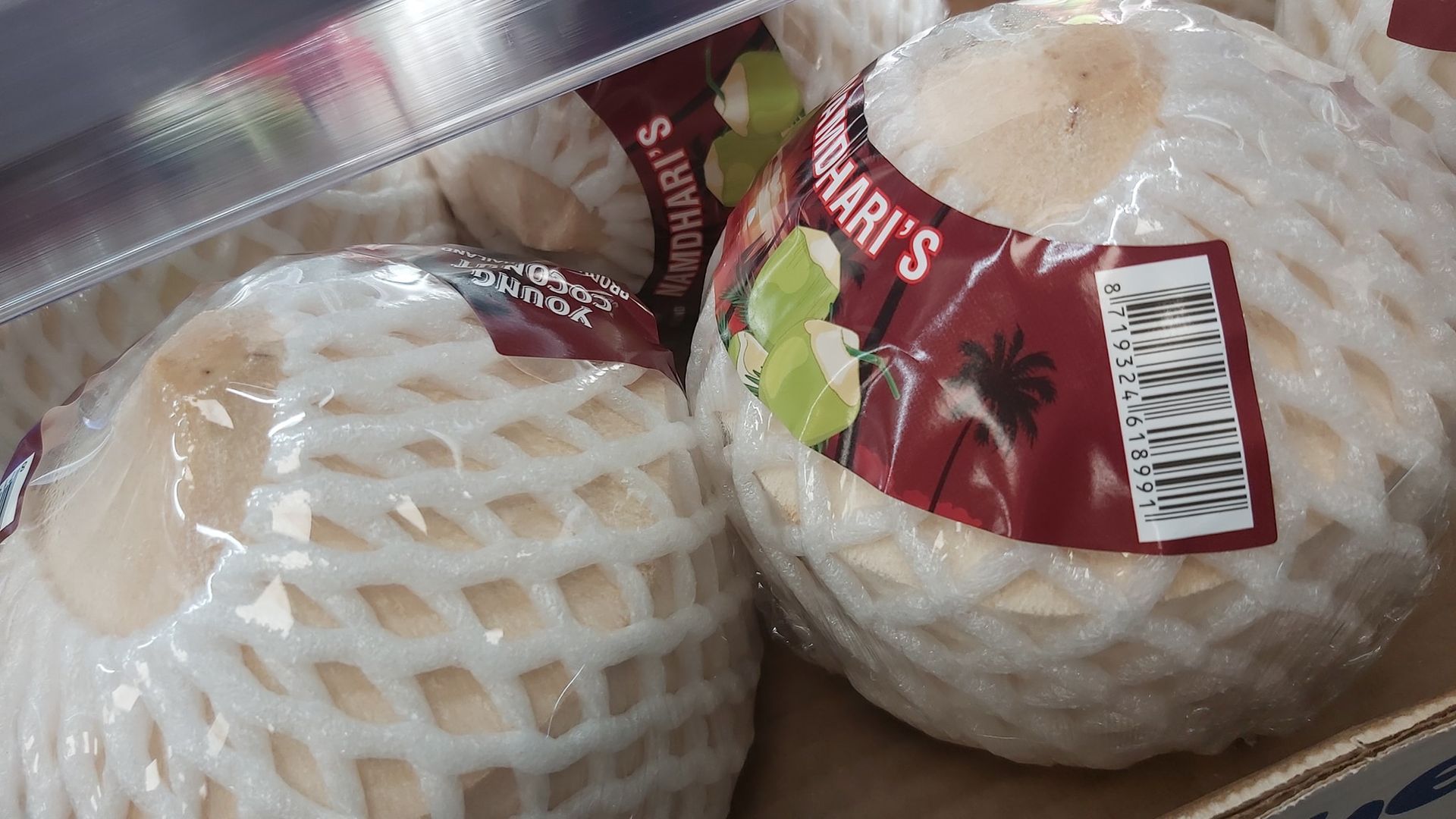 Due frutti protetti da schiuma in confezione di plastica, uno con etichetta rossa, all'interno di un espositore refrigerato.