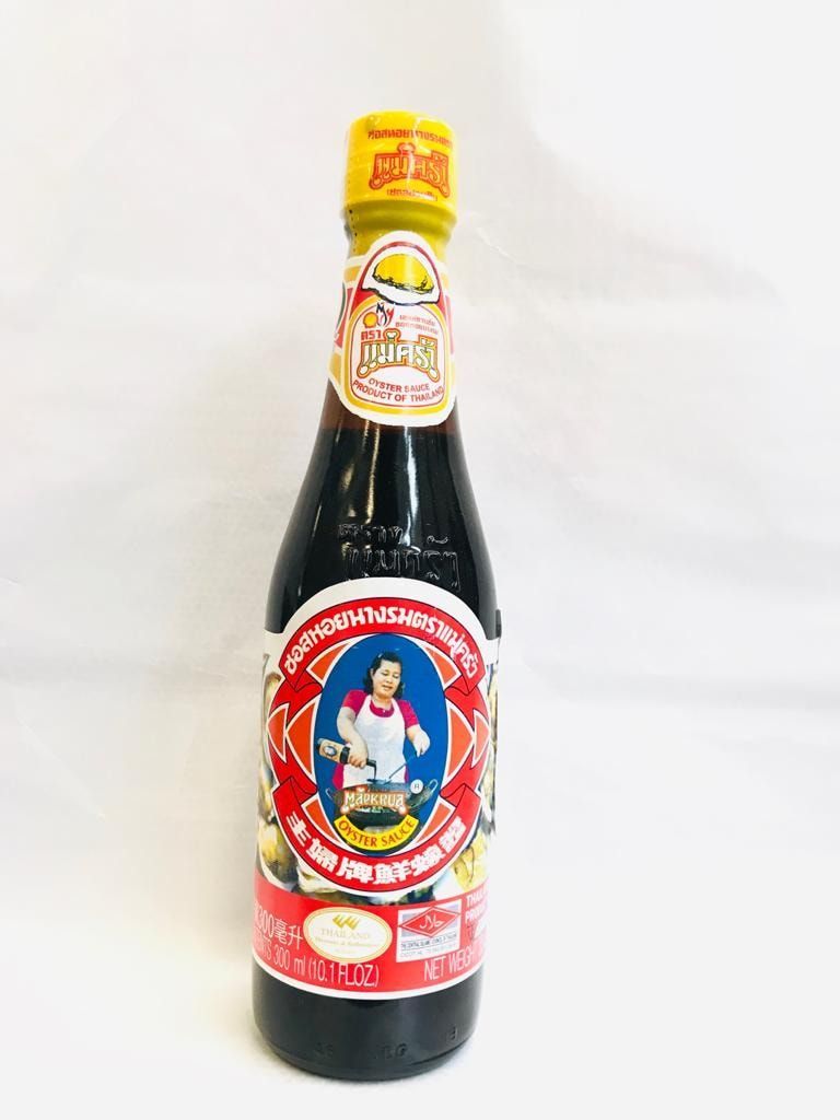 Una bottiglia di salsa scura con etichetta rossa e tappo giallo su sfondo bianco.