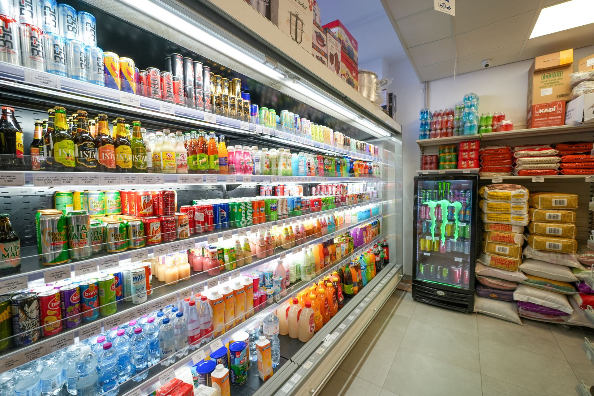 Corridoio di un supermercato con bevande e snack colorati disposti sugli scaffali e nei frigoriferi