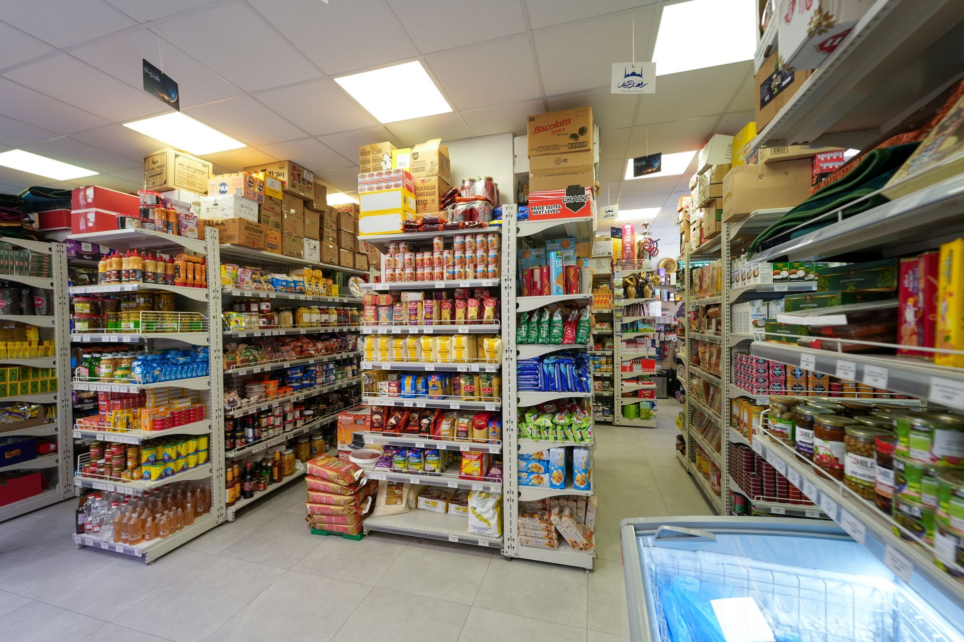 Un corridoio di un supermercato ben illuminato, con scaffali pieni di snack, bevande e prodotti confezionati.