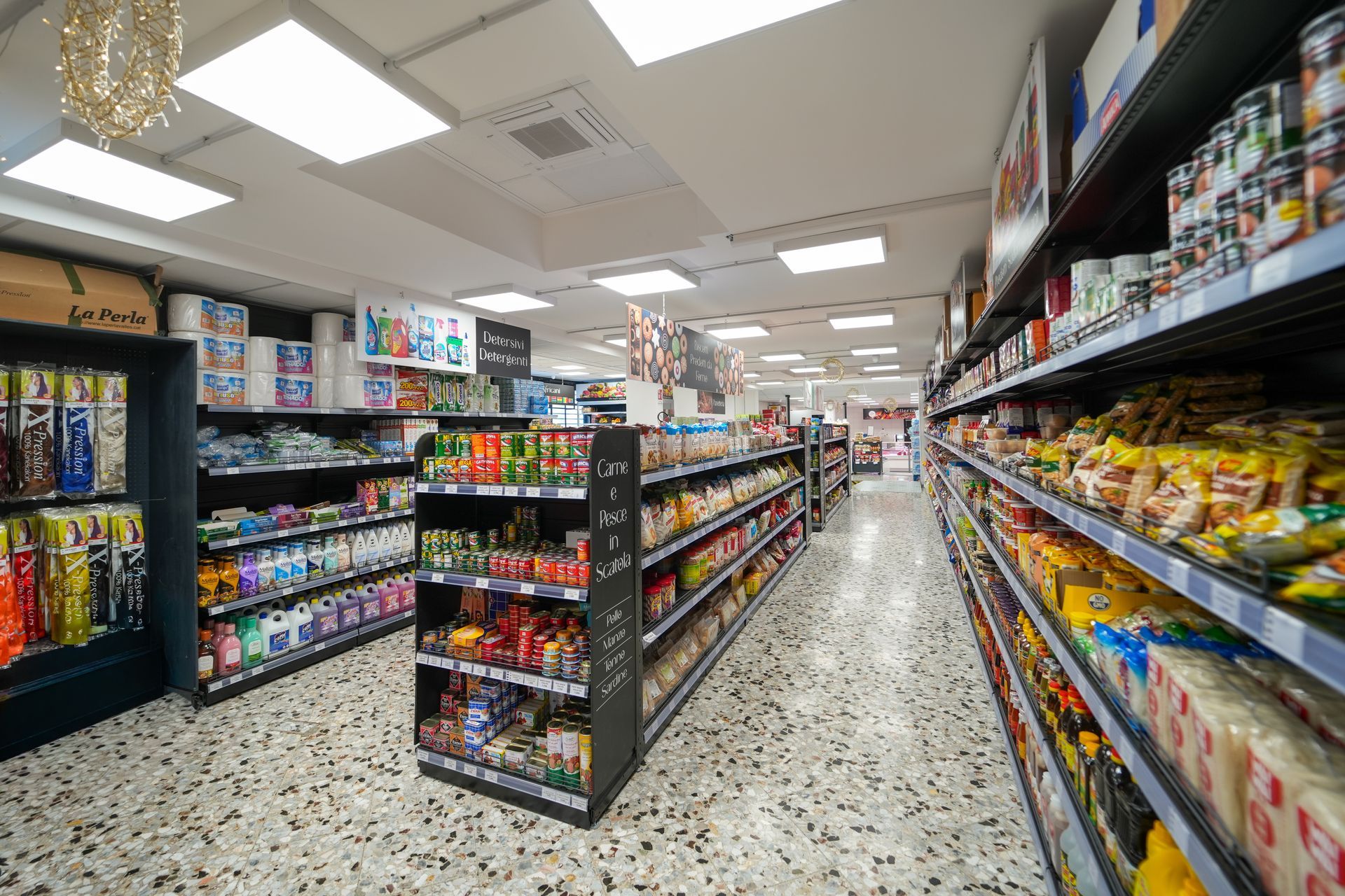 Un corridoio di un supermercato ben illuminato, con scaffali pieni di snack e bevande su entrambi i lati.