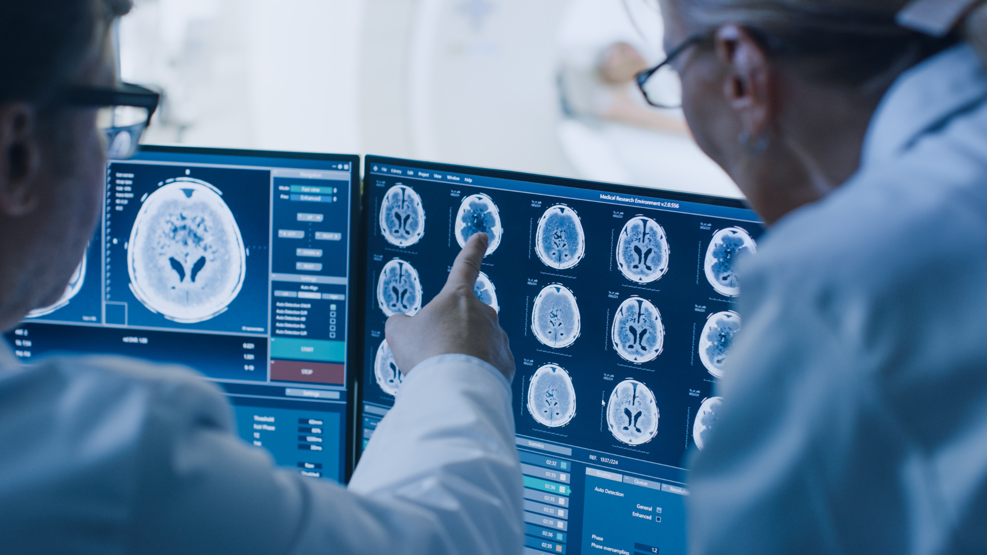 Two doctors are looking at a brain scan on a computer screen.