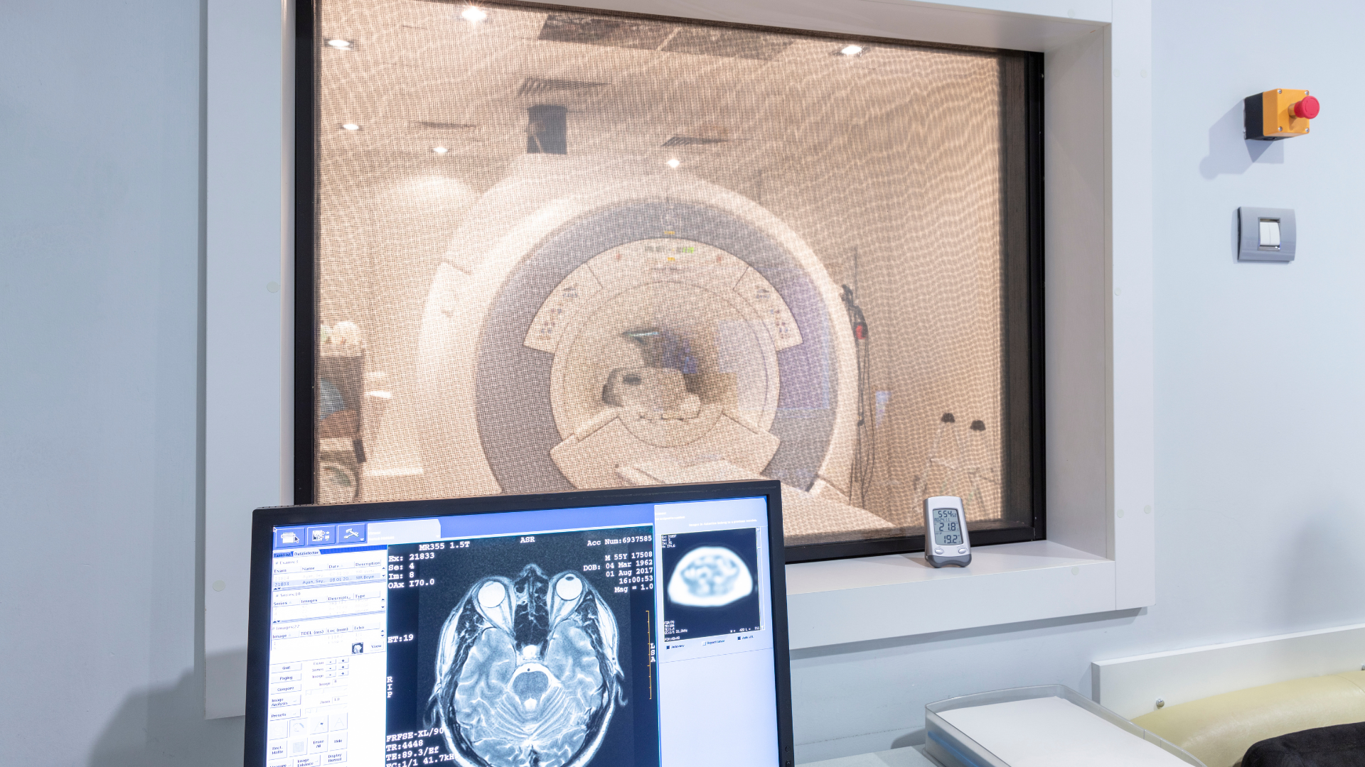 A computer monitor is sitting in front of a mri machine.