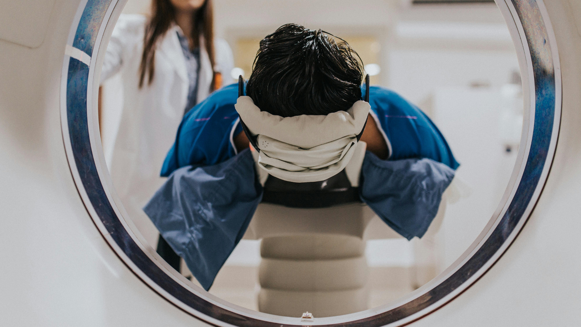 A man is sitting in a chair getting a ct scan.