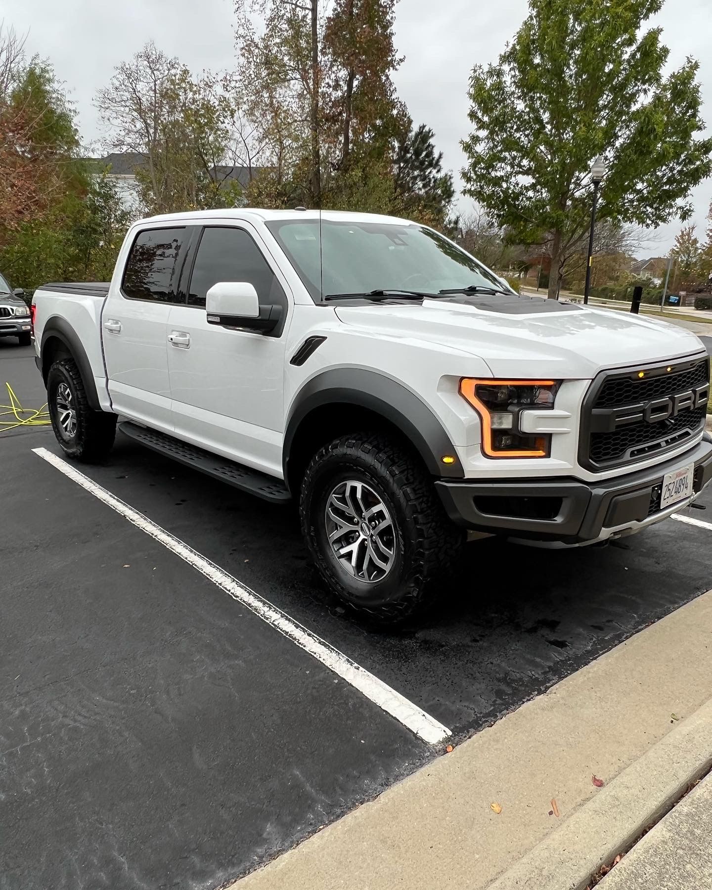 White Ford Raptor pickup truck parked in a parking space.