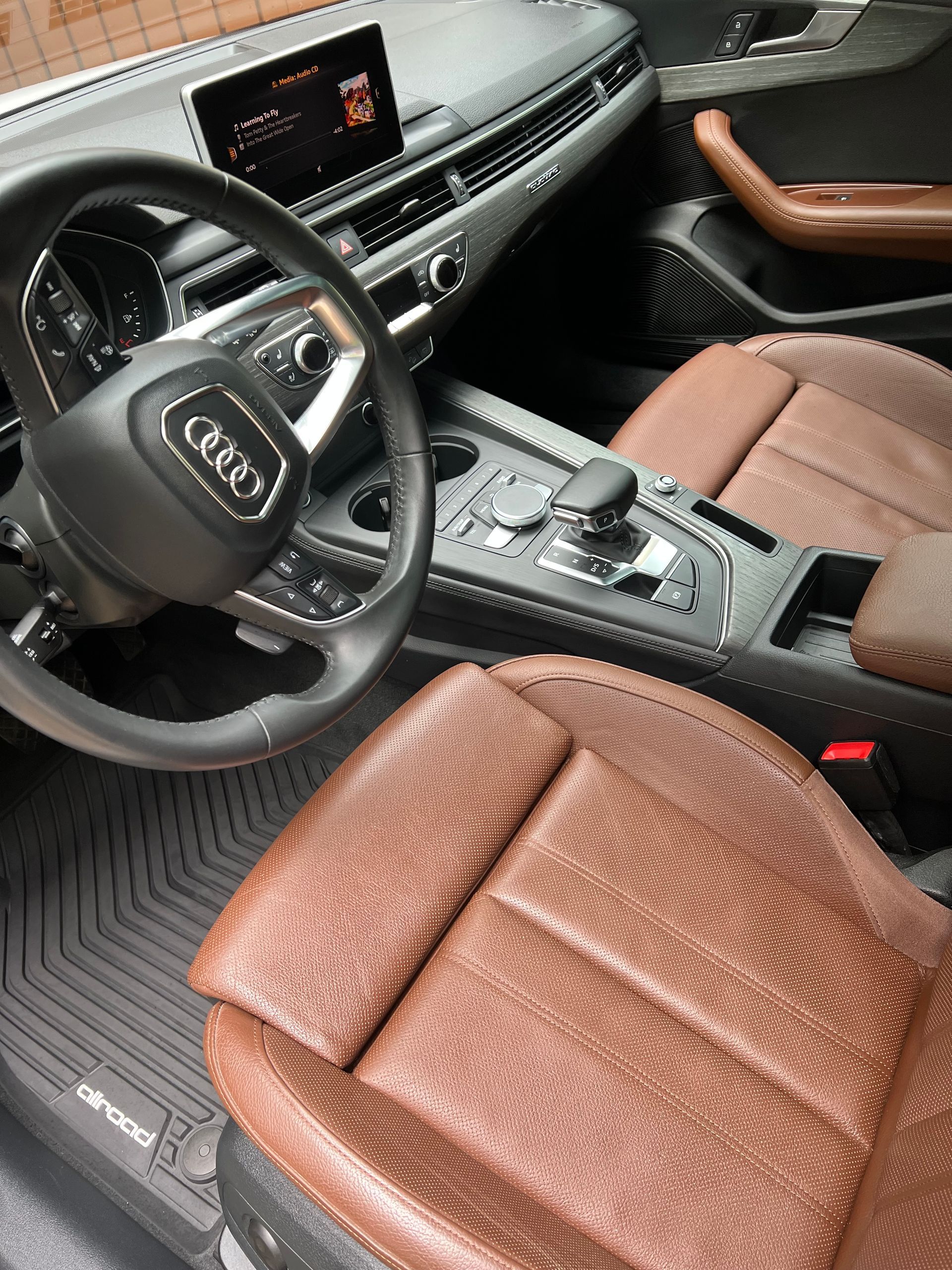 Interior of a brown leather Audi. Steering wheel, dashboard, center console, and seats are visible.