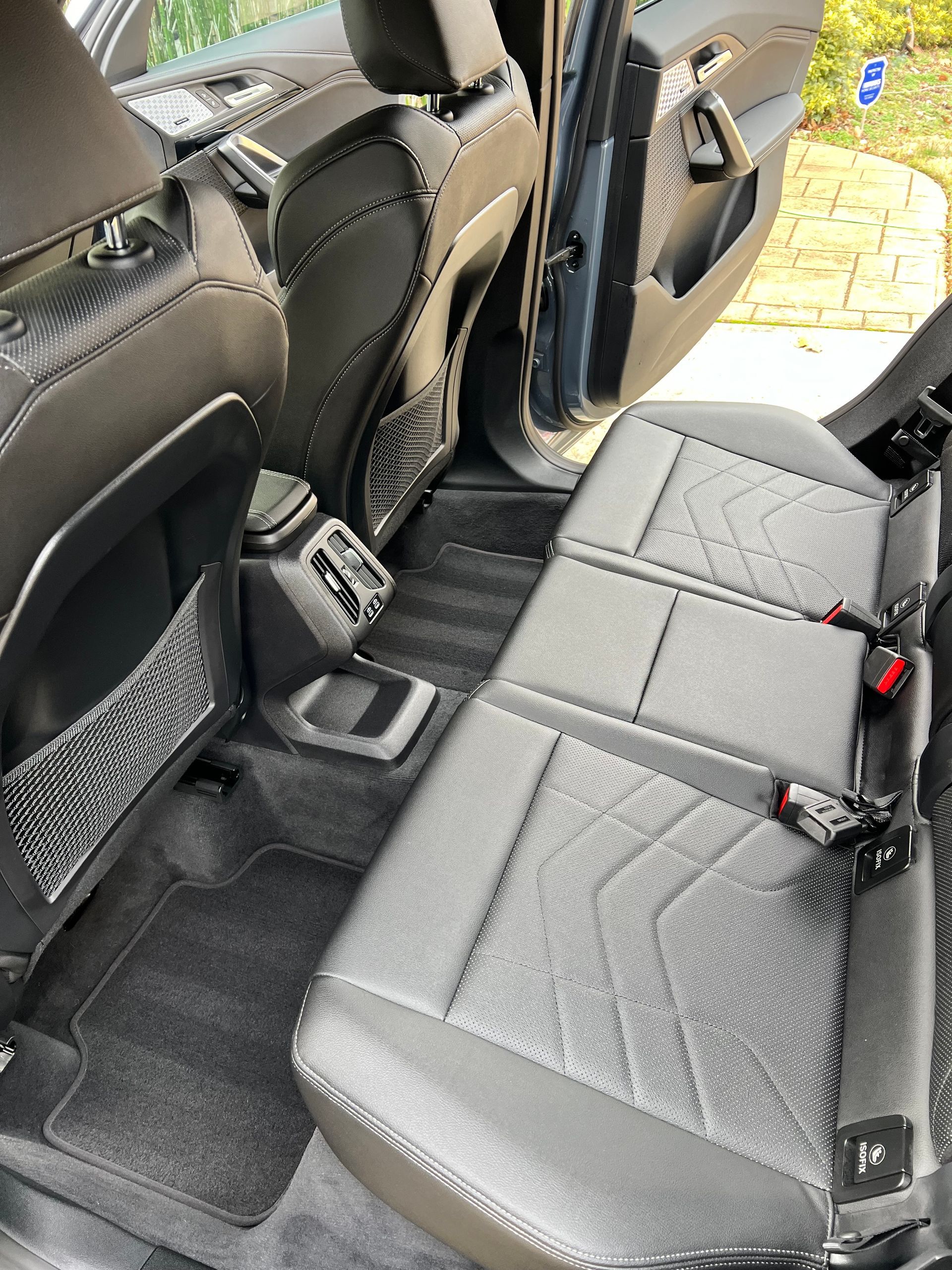 Gray car backseats with geometric stitching, black side pockets, and a gray carpet.