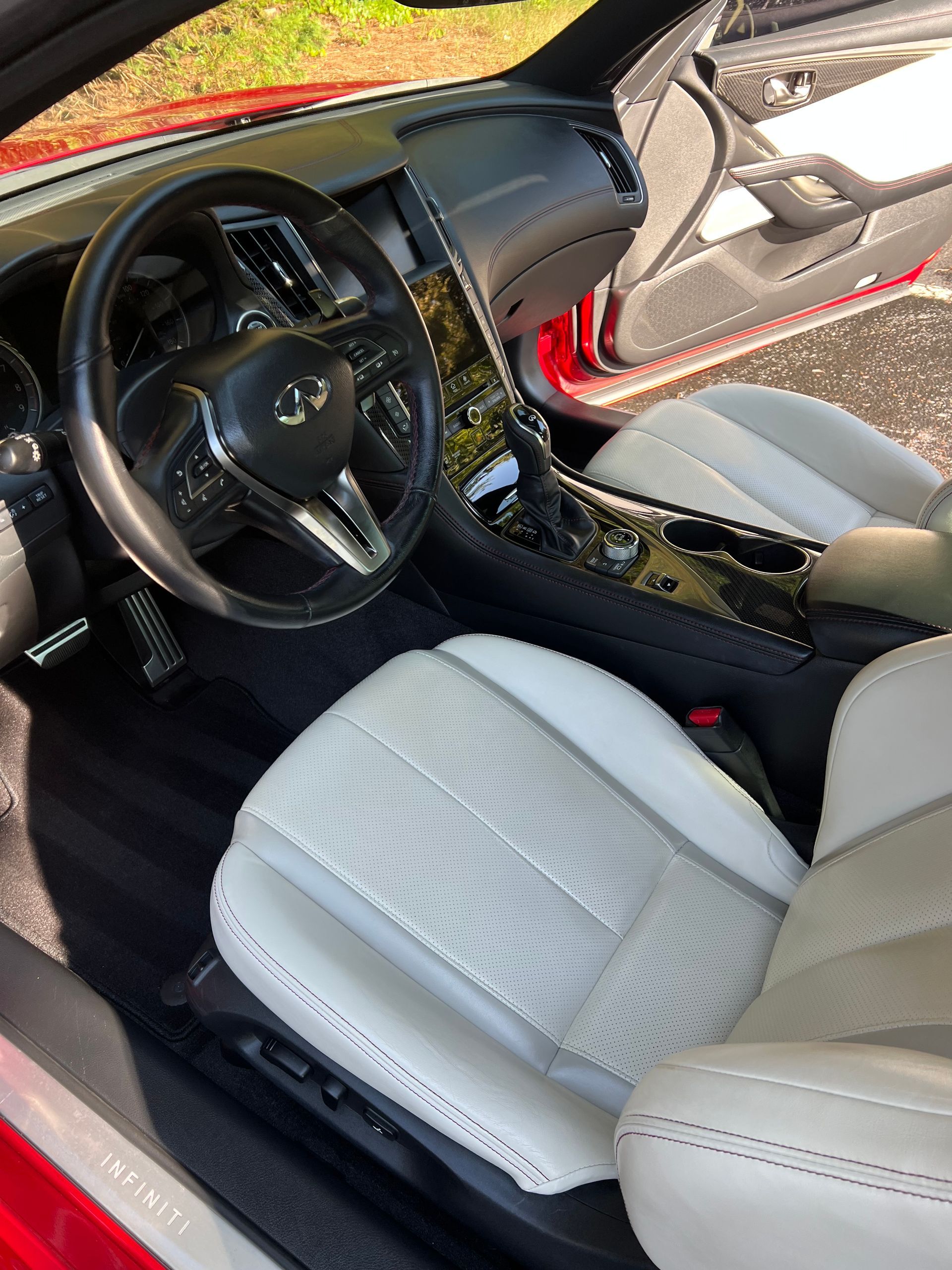 Interior of a red car with white perforated leather seats, black dashboard, and silver accents.