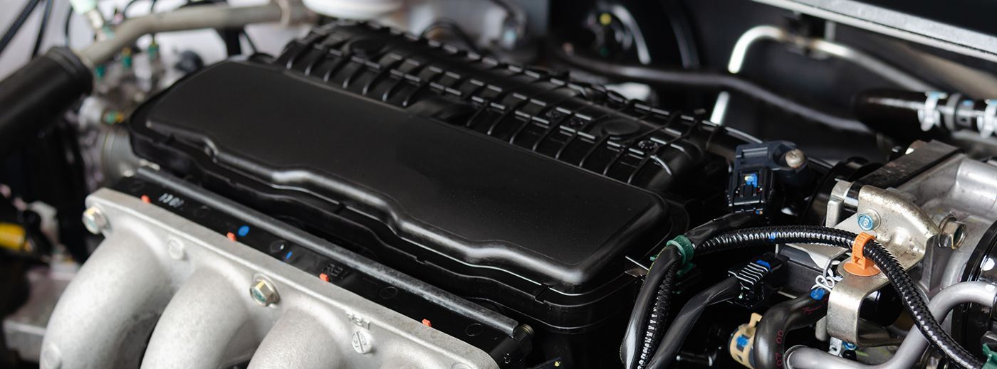 Car engine, primarily black and silver, with various hoses and components visible.