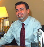 A man in a shirt and tie is sitting at a desk