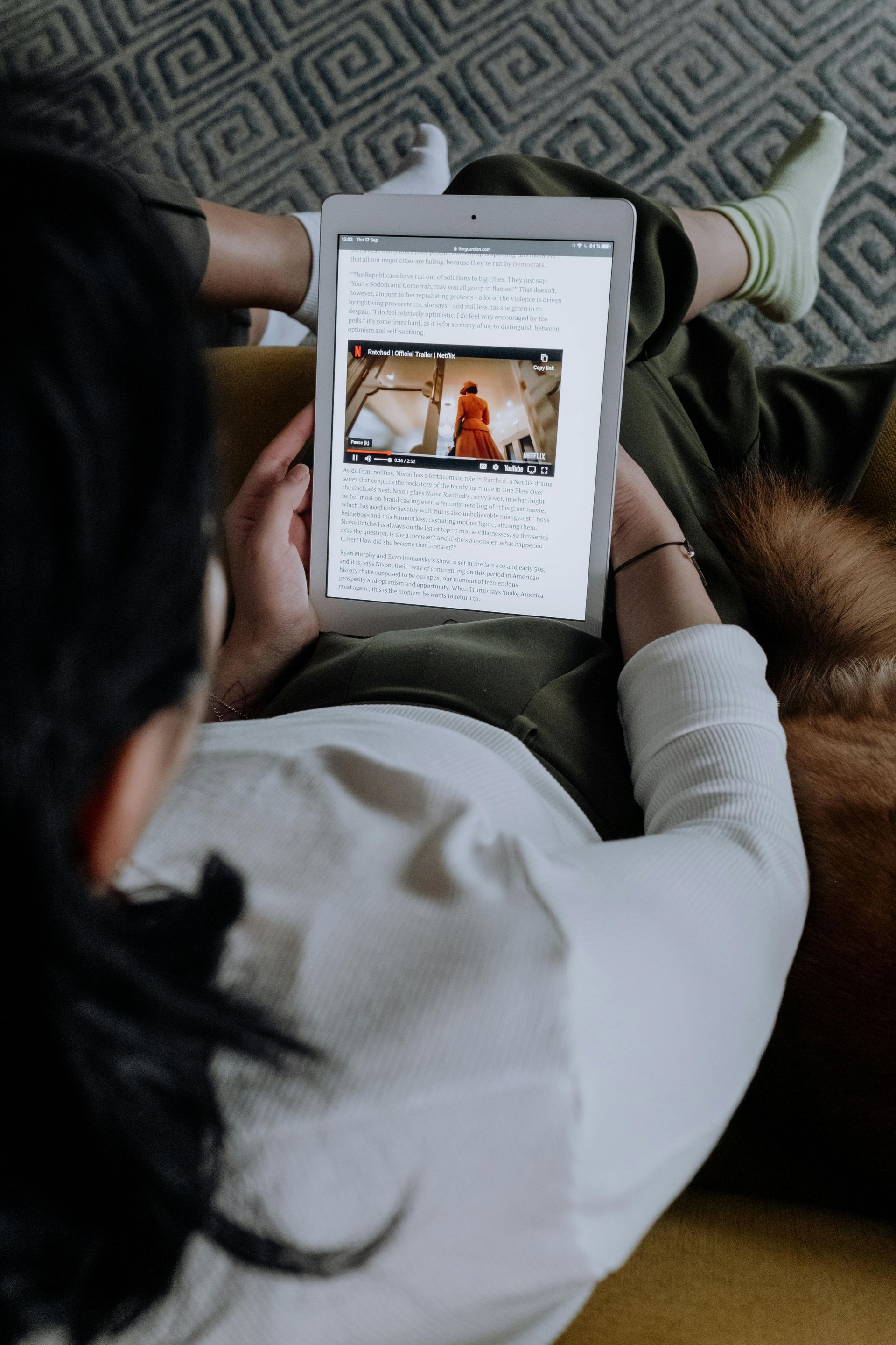 A woman is sitting on a couch using a tablet computer.