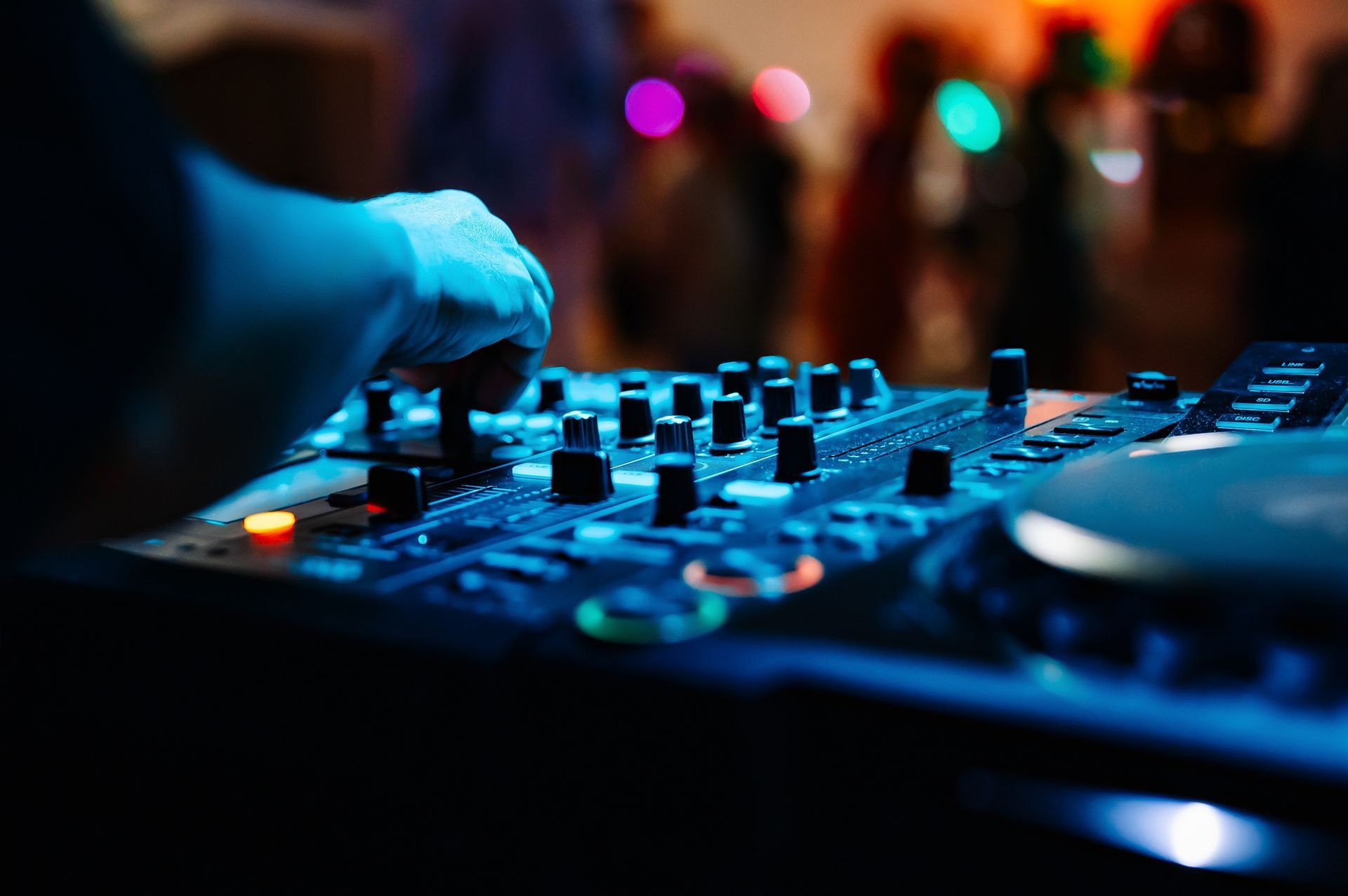 A dj is playing music on a mixer at a party.