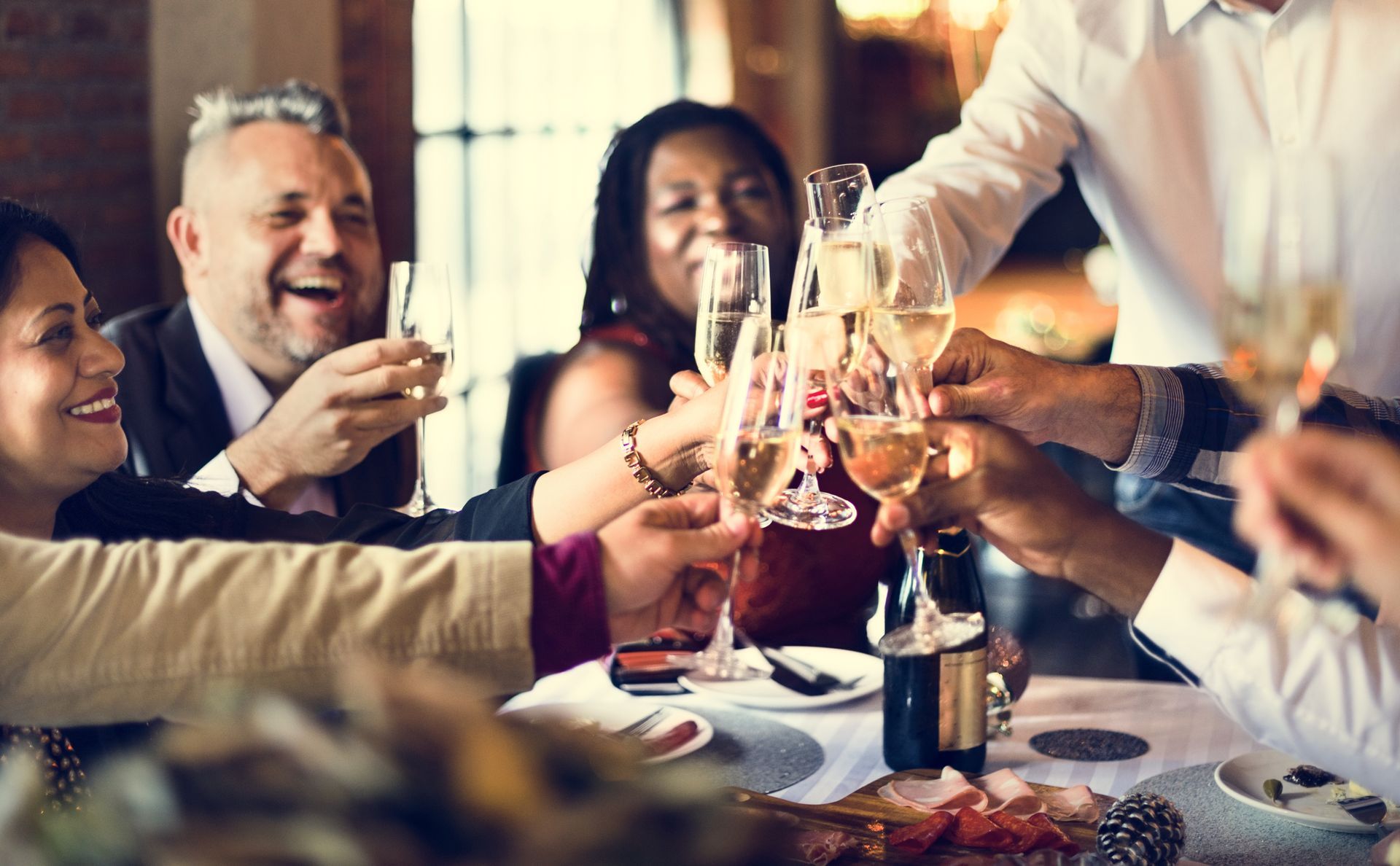 A group of people are sitting at a table toasting with champagne glasses.