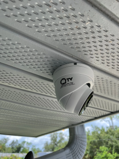 Outdoor dome security camera installed under home soffit by Quality TV Smart Home and Security for residential video surveillance and home protection.