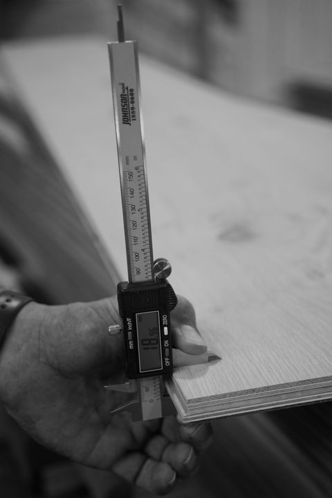 A person is measuring a piece of wood with a digital caliper