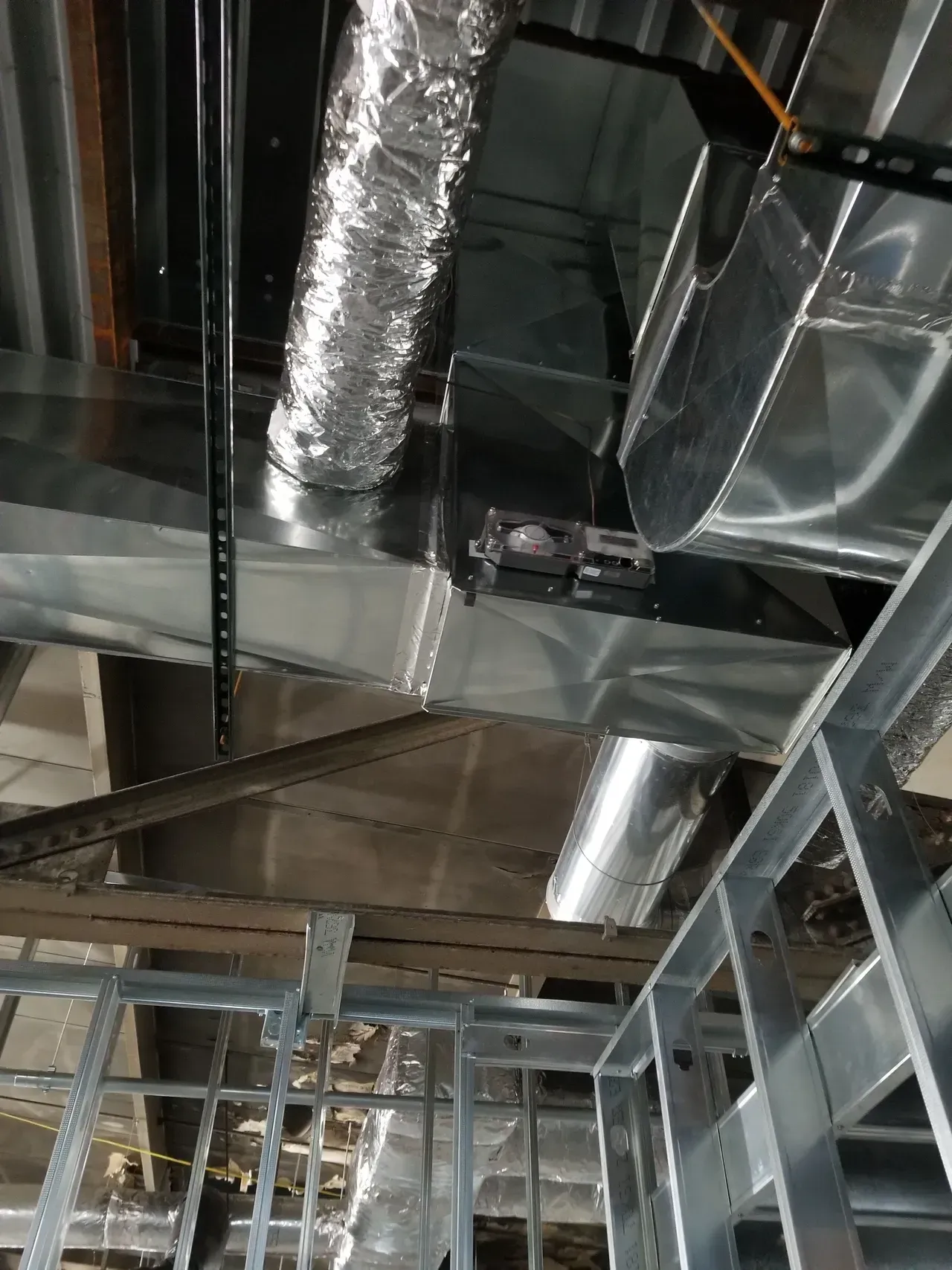 A building under construction with a lot of metal pipes hanging from the ceiling.