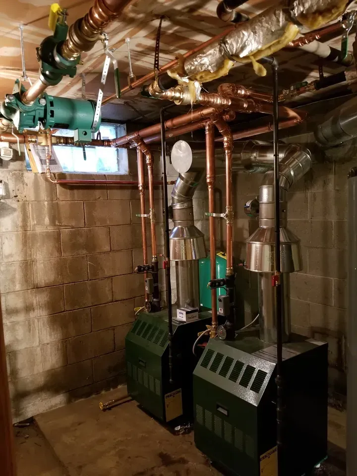 A room with a lot of pipes and boilers in it.