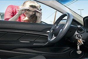 Woman looking into a car, hands on head, keys hanging in the ignition.