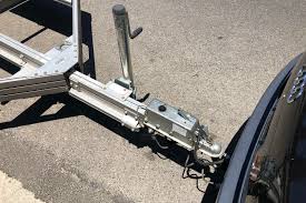 Boat trailer hitch connected to a car. Silver metal and gray asphalt.