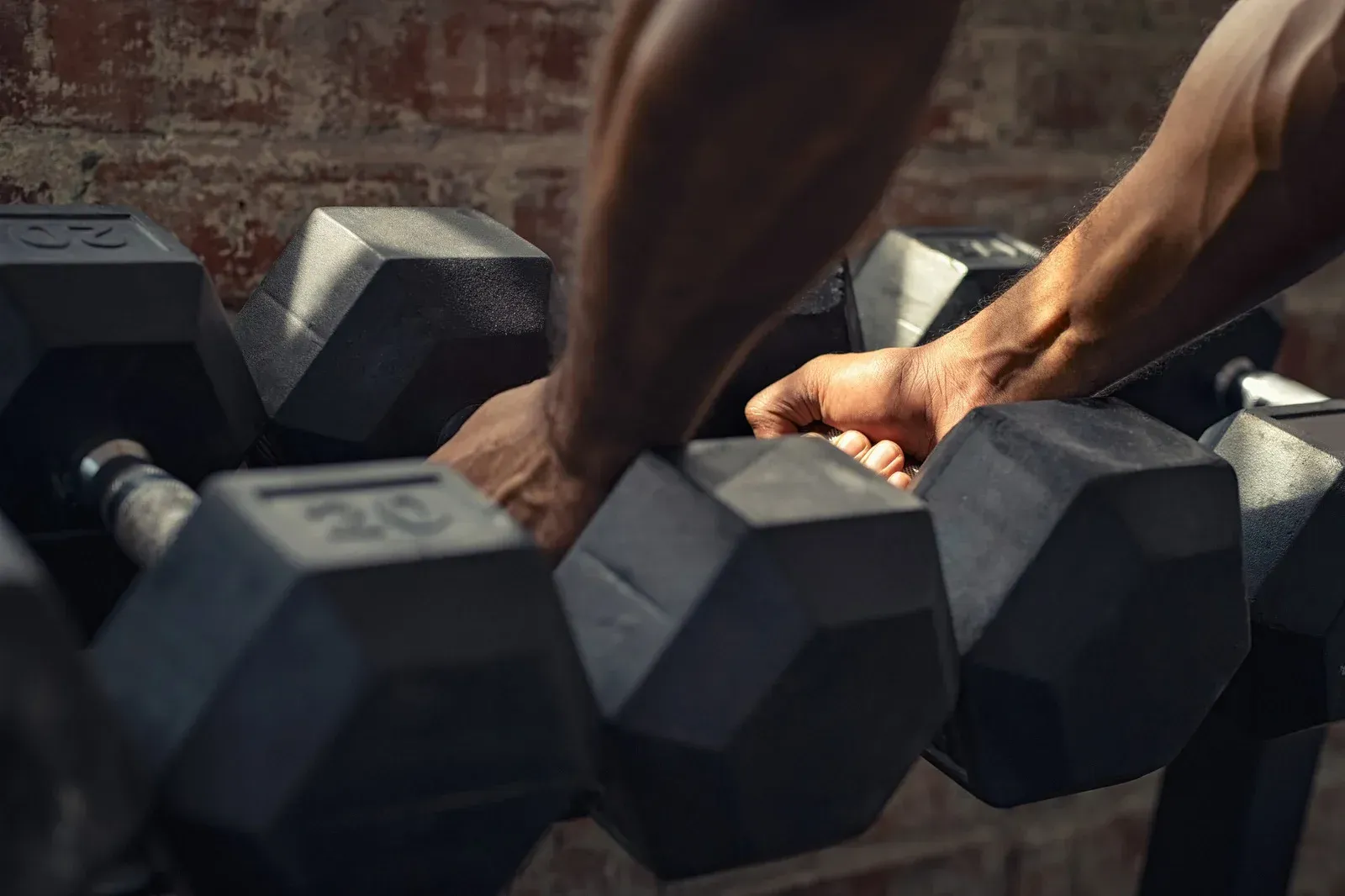 People lifting barbells in a gym. Man and woman bend over the weight, preparing to lift.