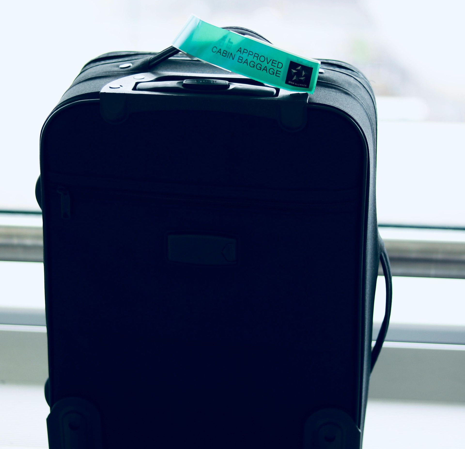 Mala de viagem preta com rodinhas e etiqueta verde.