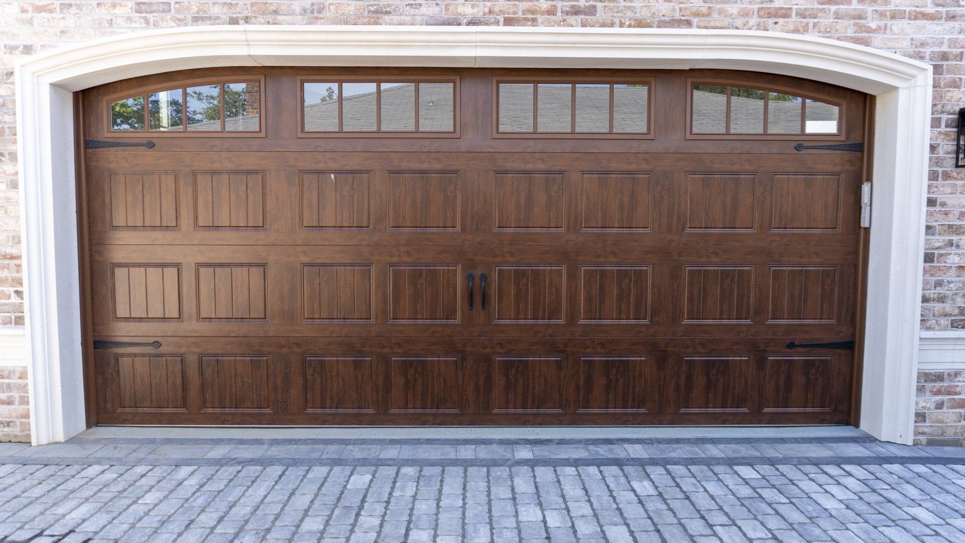 A large wooden garage door is sitting in front of a brick building.