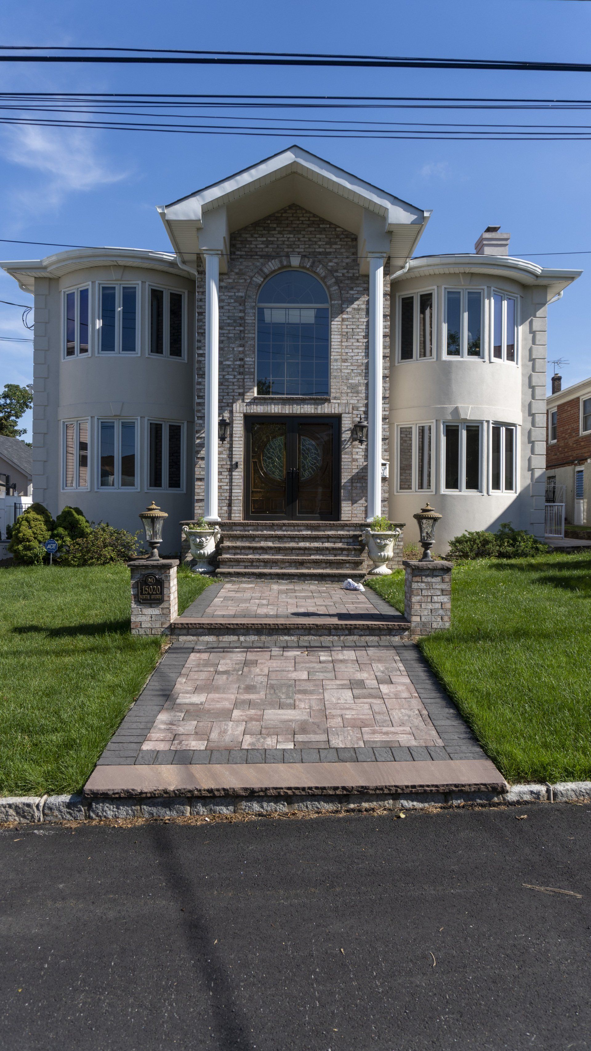 A large white house with a brick walkway leading to it.