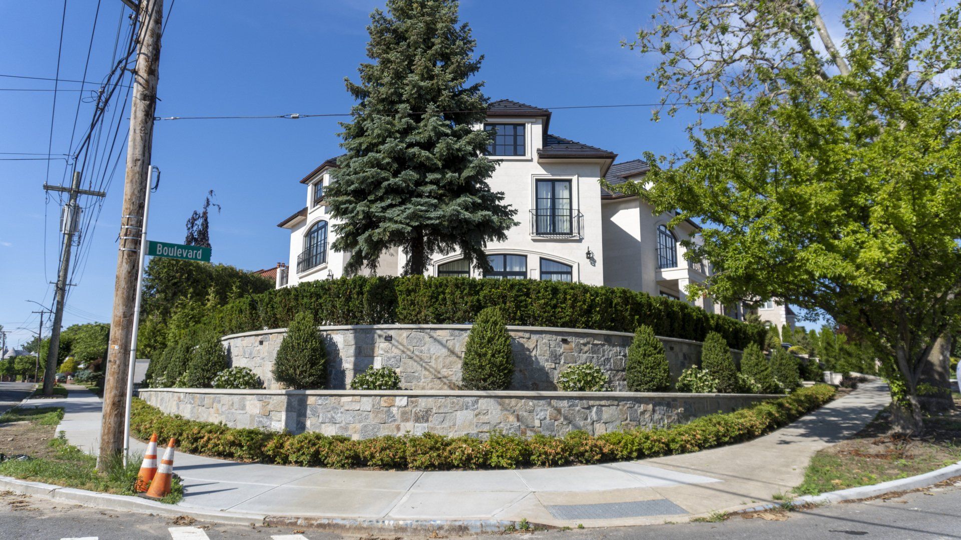 A large white house is sitting on the corner of a street.