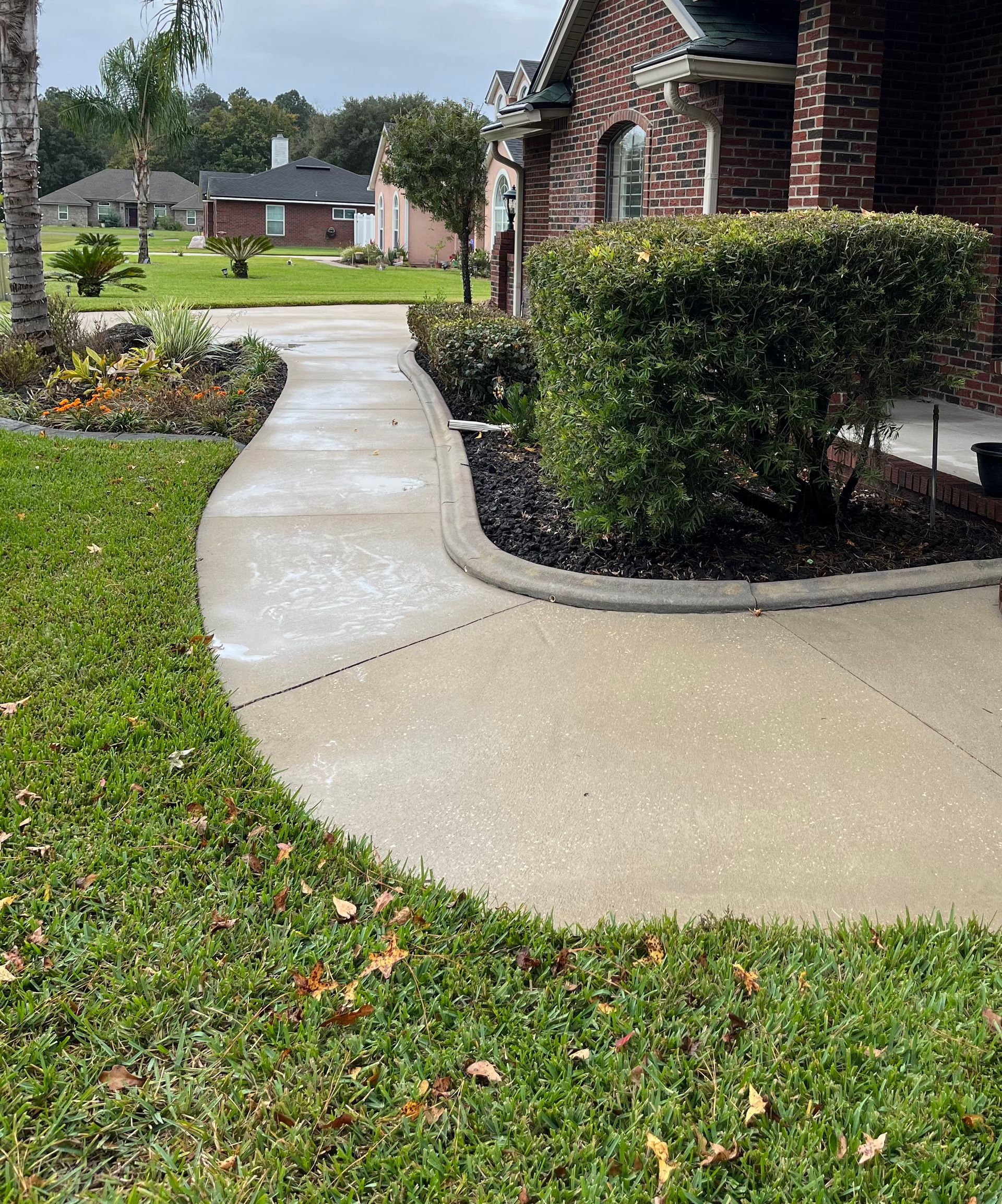 A brick house with a concrete walkway leading to it