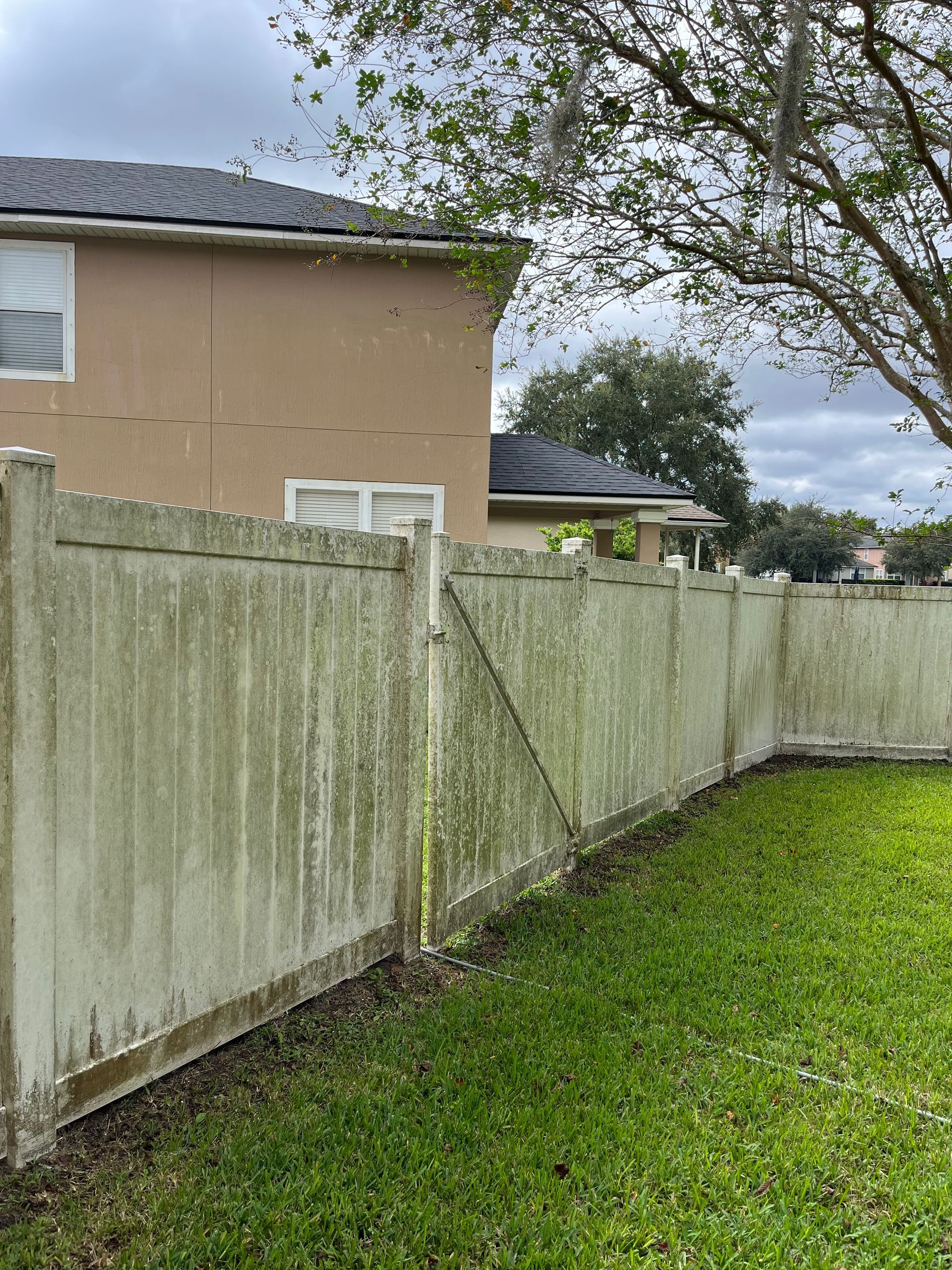 A dirty wooden fence in a backyard next to a house.