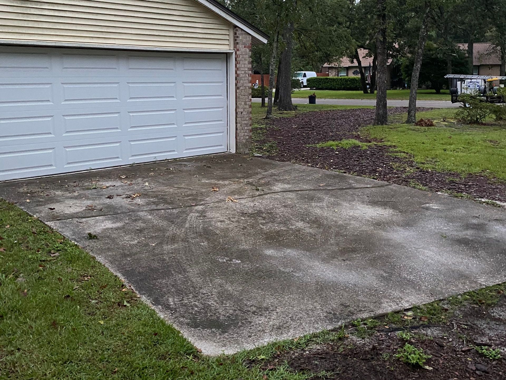 A concrete driveway in front of a garage with a white garage door.