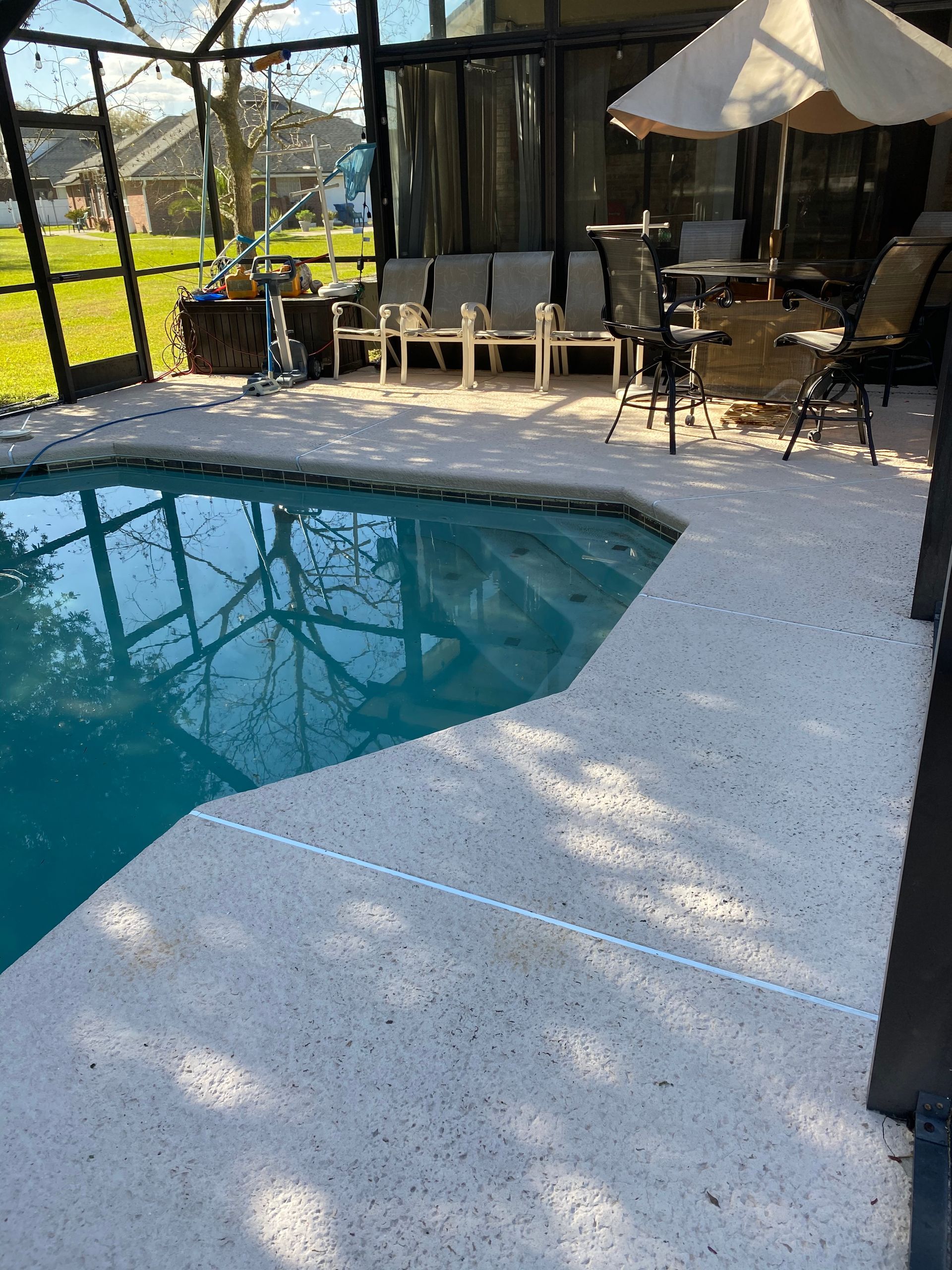 A swimming pool with a white umbrella and chairs around it