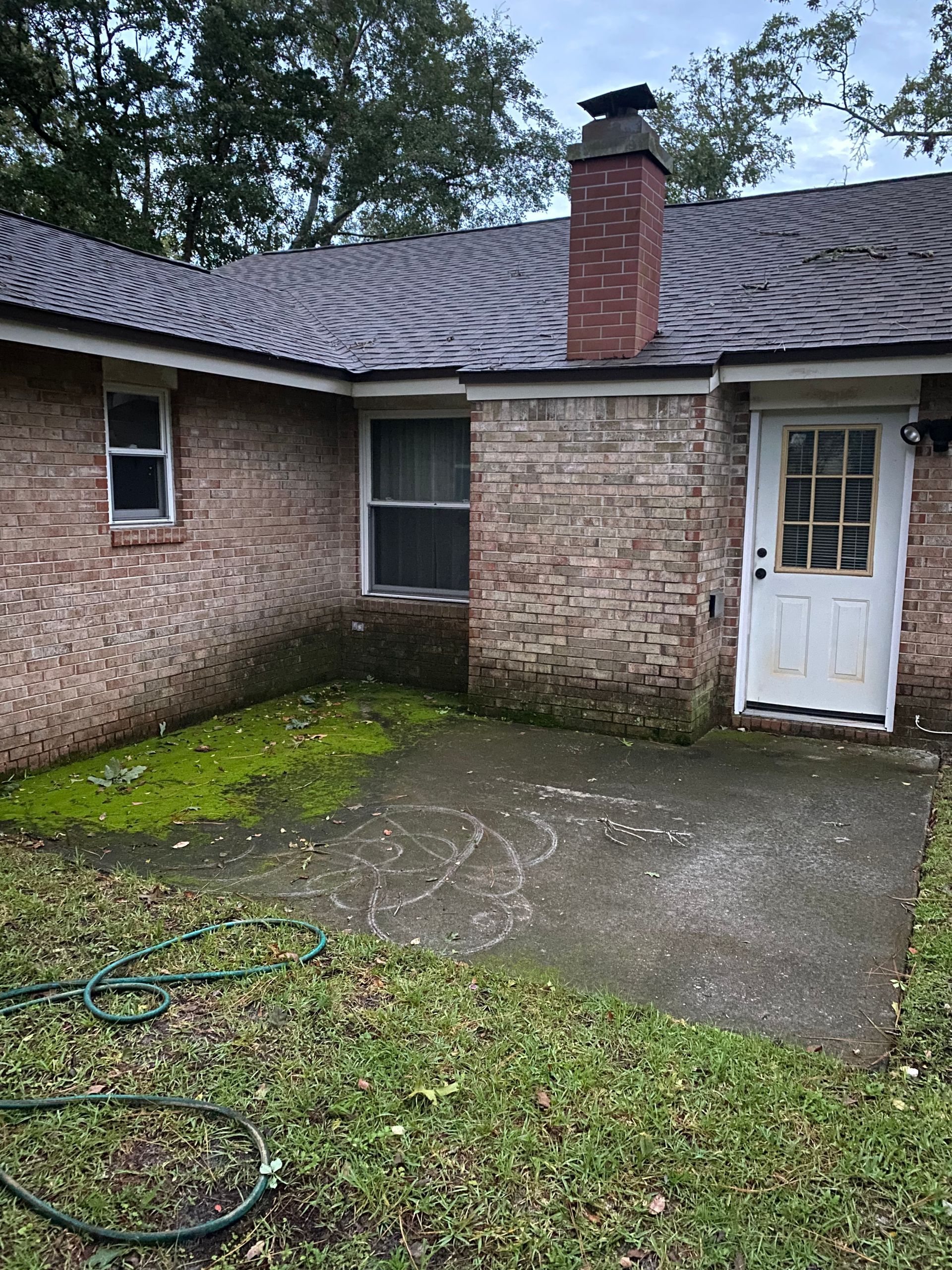 A brick house with a white door and a hose in front of it.