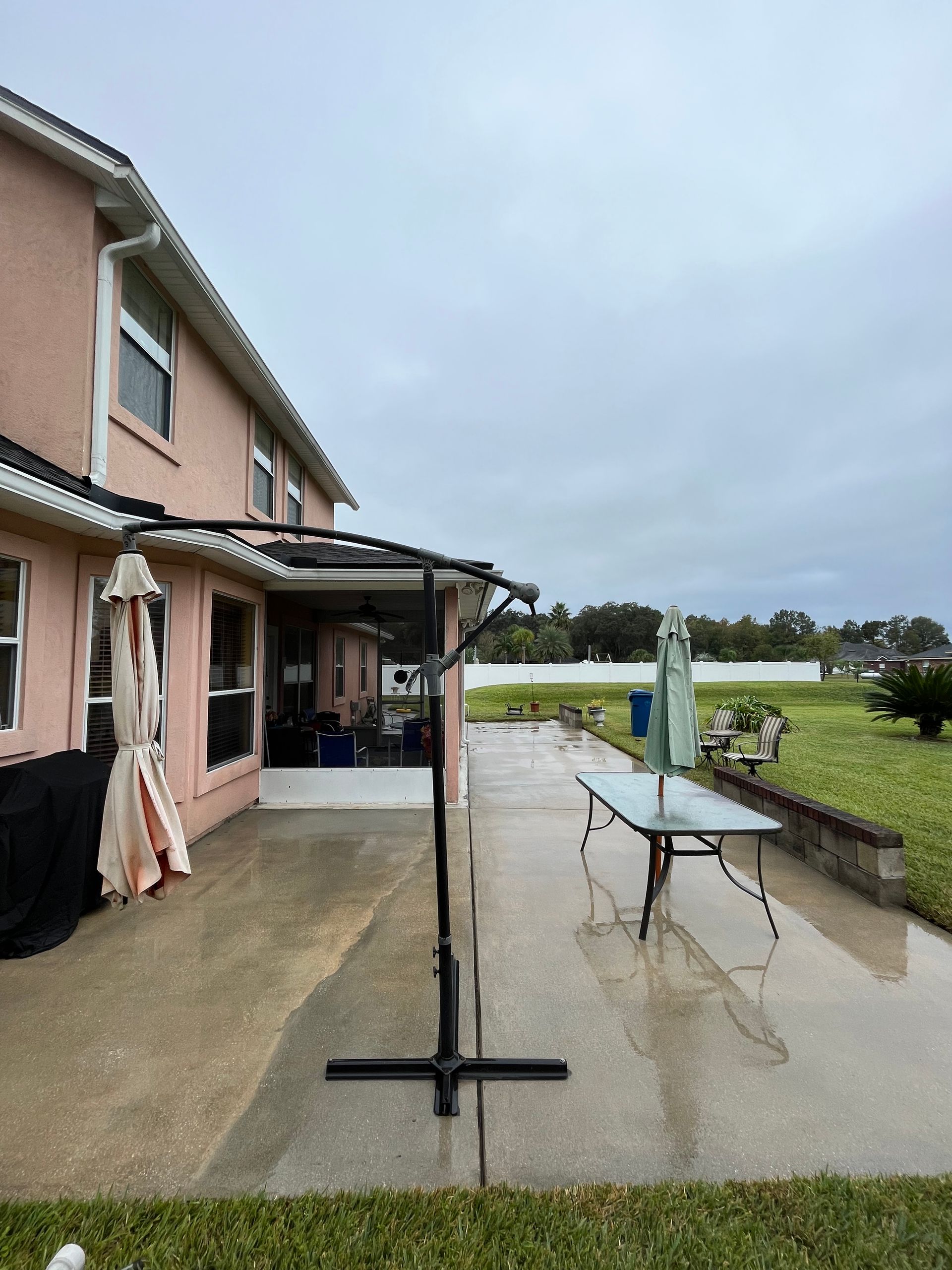 A patio with a table and umbrellas in front of a house.