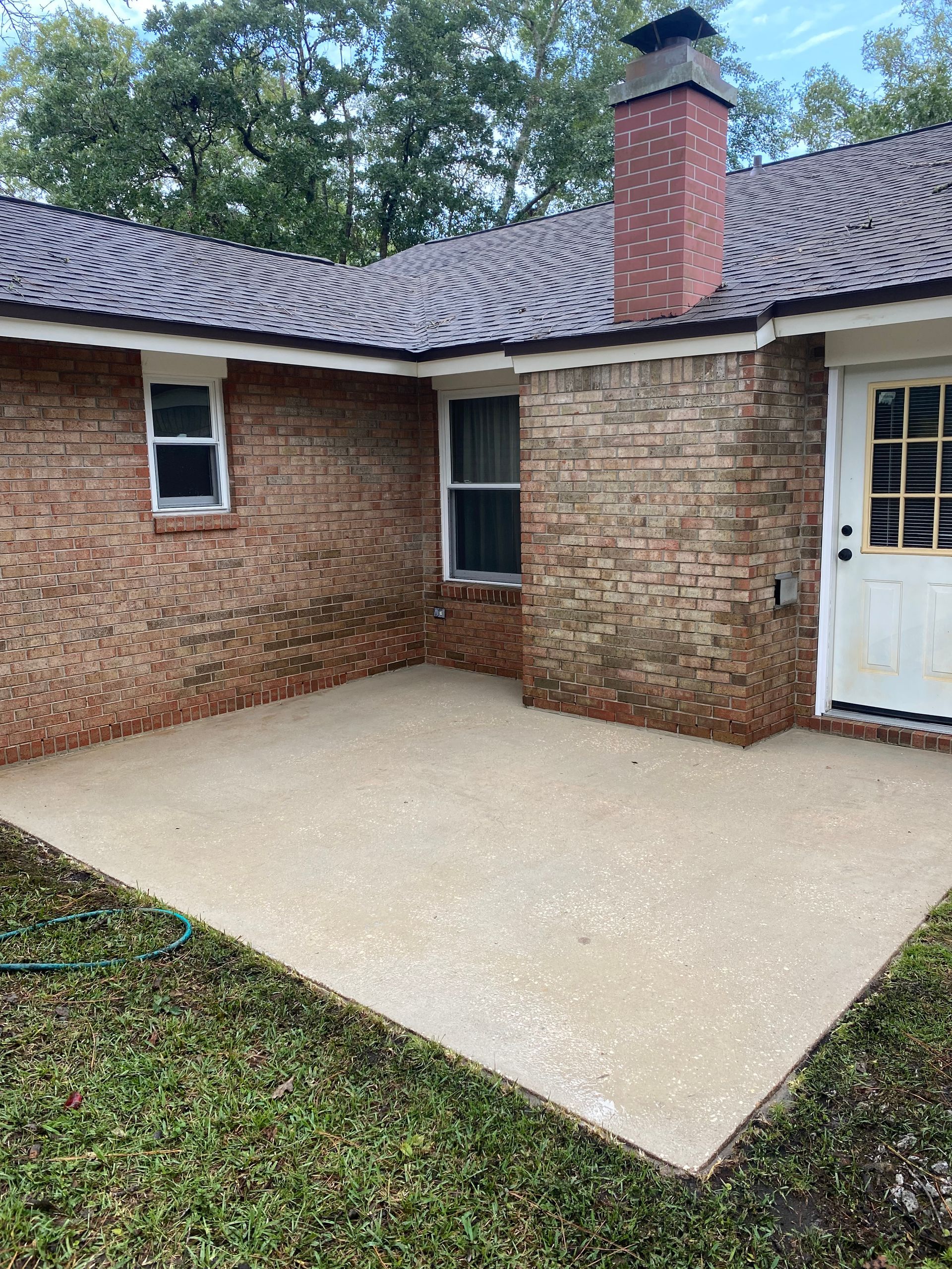 A brick house with a concrete patio in front of it.