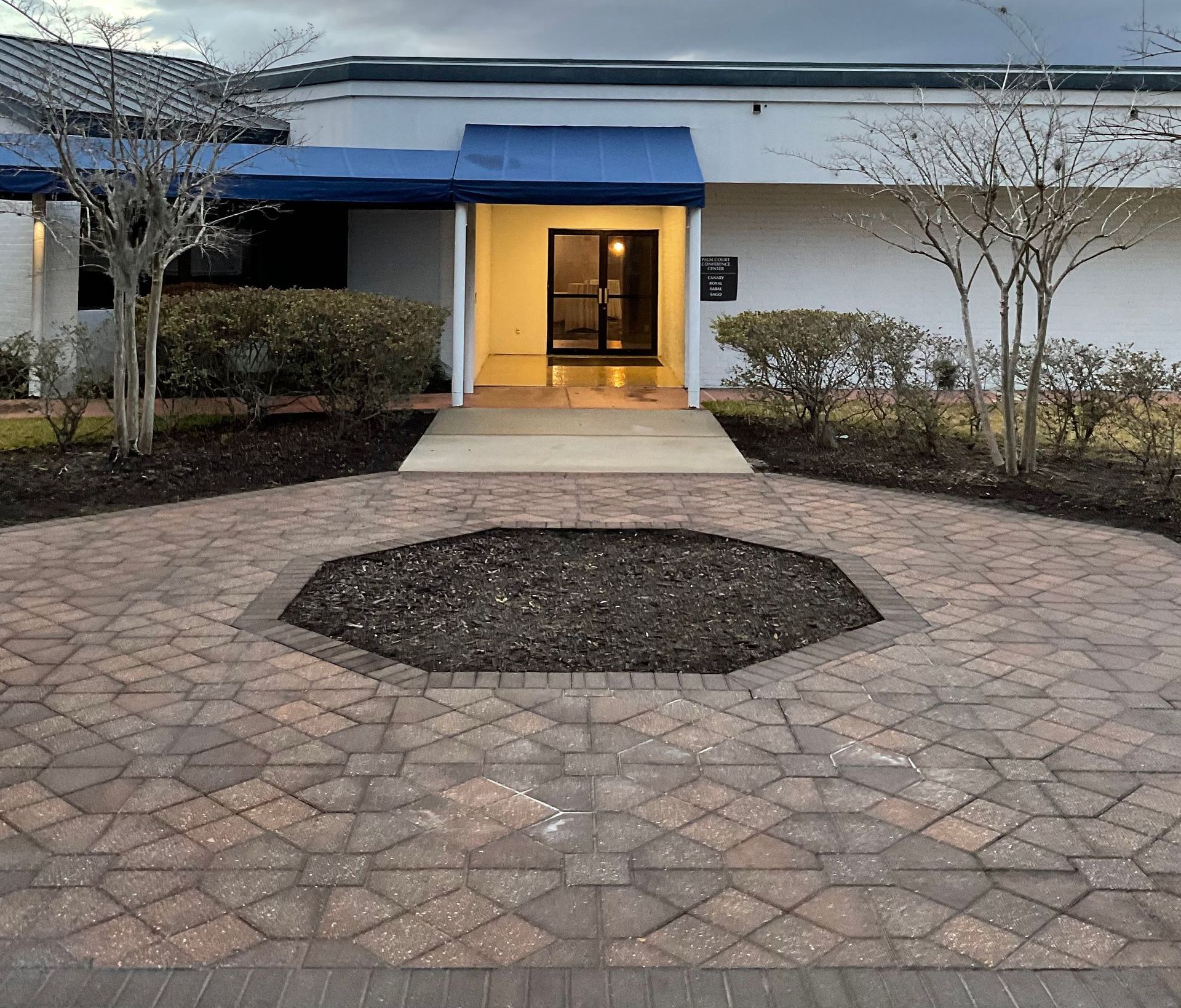 A white building with a blue awning and a brick walkway