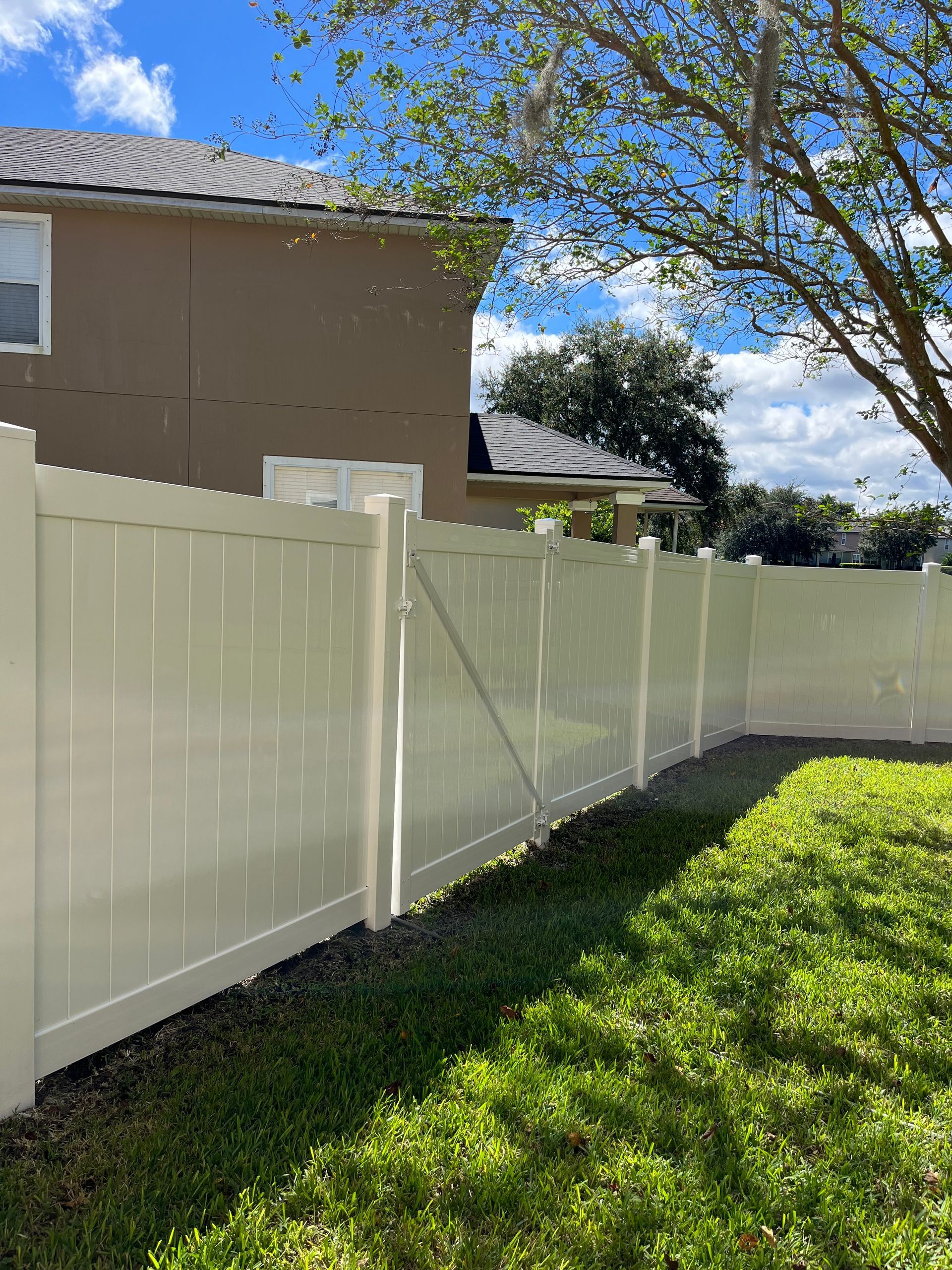 A white vinyl fence is in the backyard of a house.