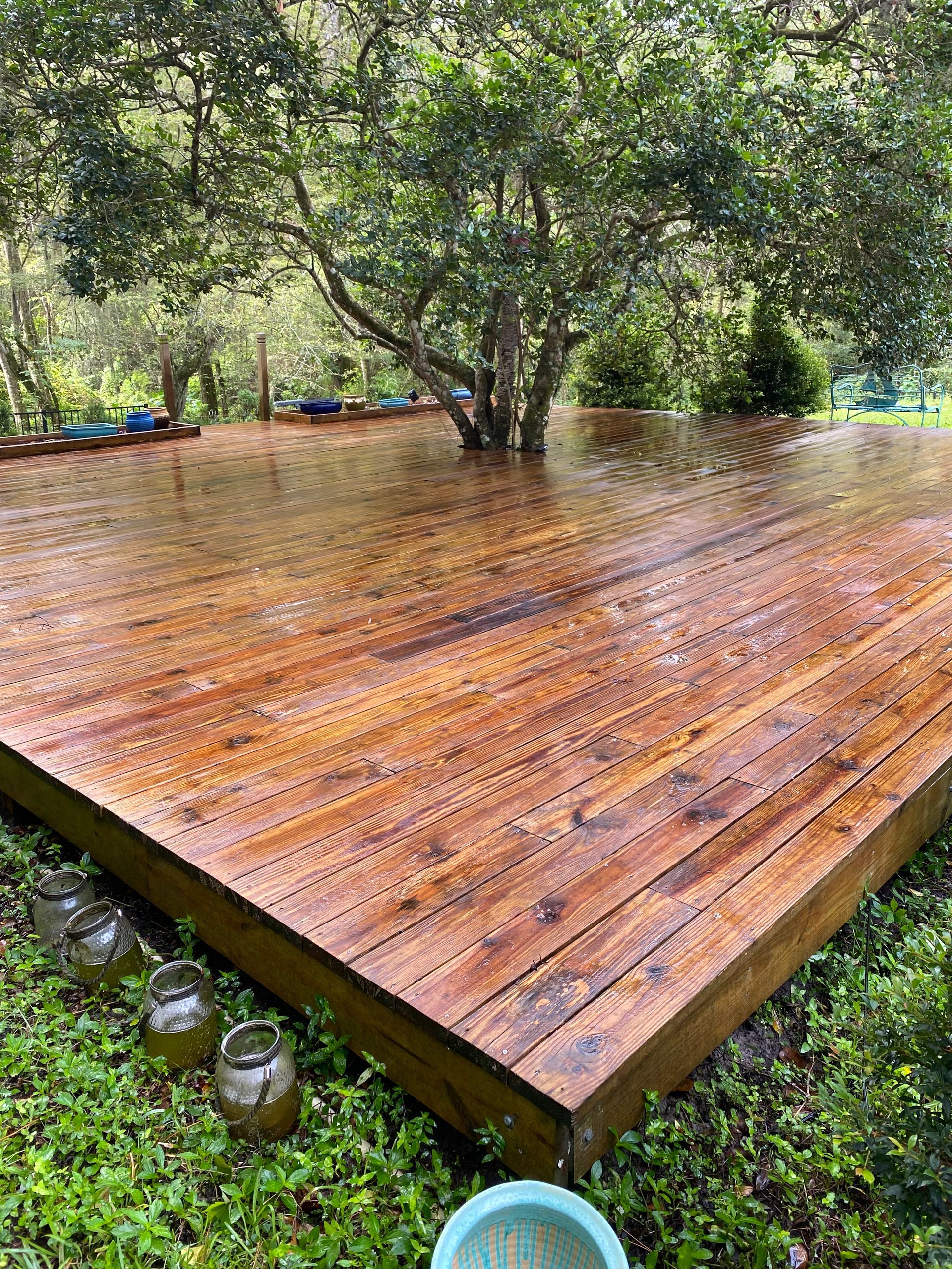 A wooden deck is sitting on top of a lush green field surrounded by trees.