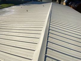 A white metal roof with a gutter on the side of it.