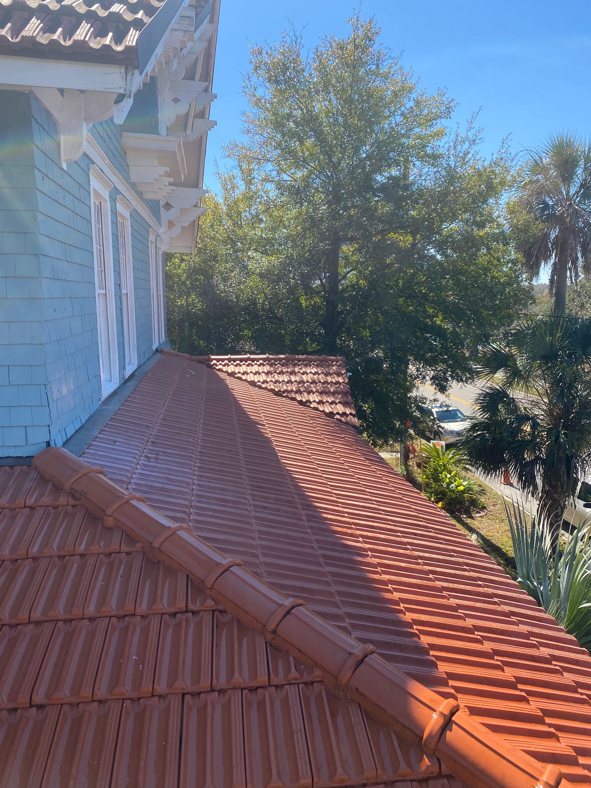 A house with a red tiled roof and trees in the background