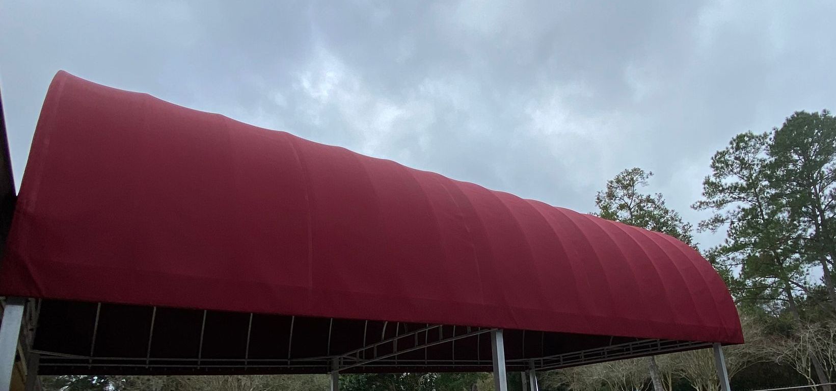 A red awning is sitting under a cloudy sky.