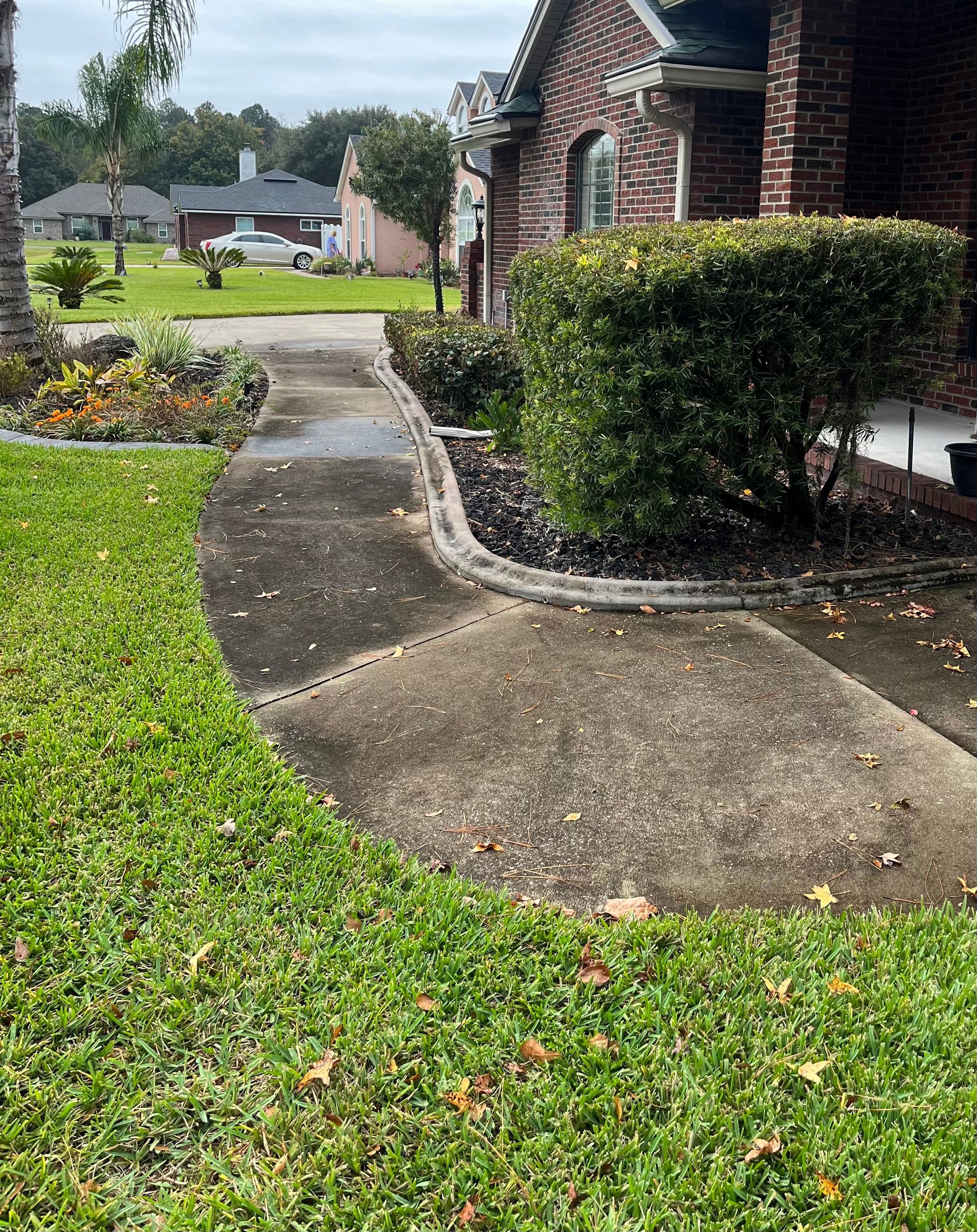 A brick house with a concrete walkway leading to it.