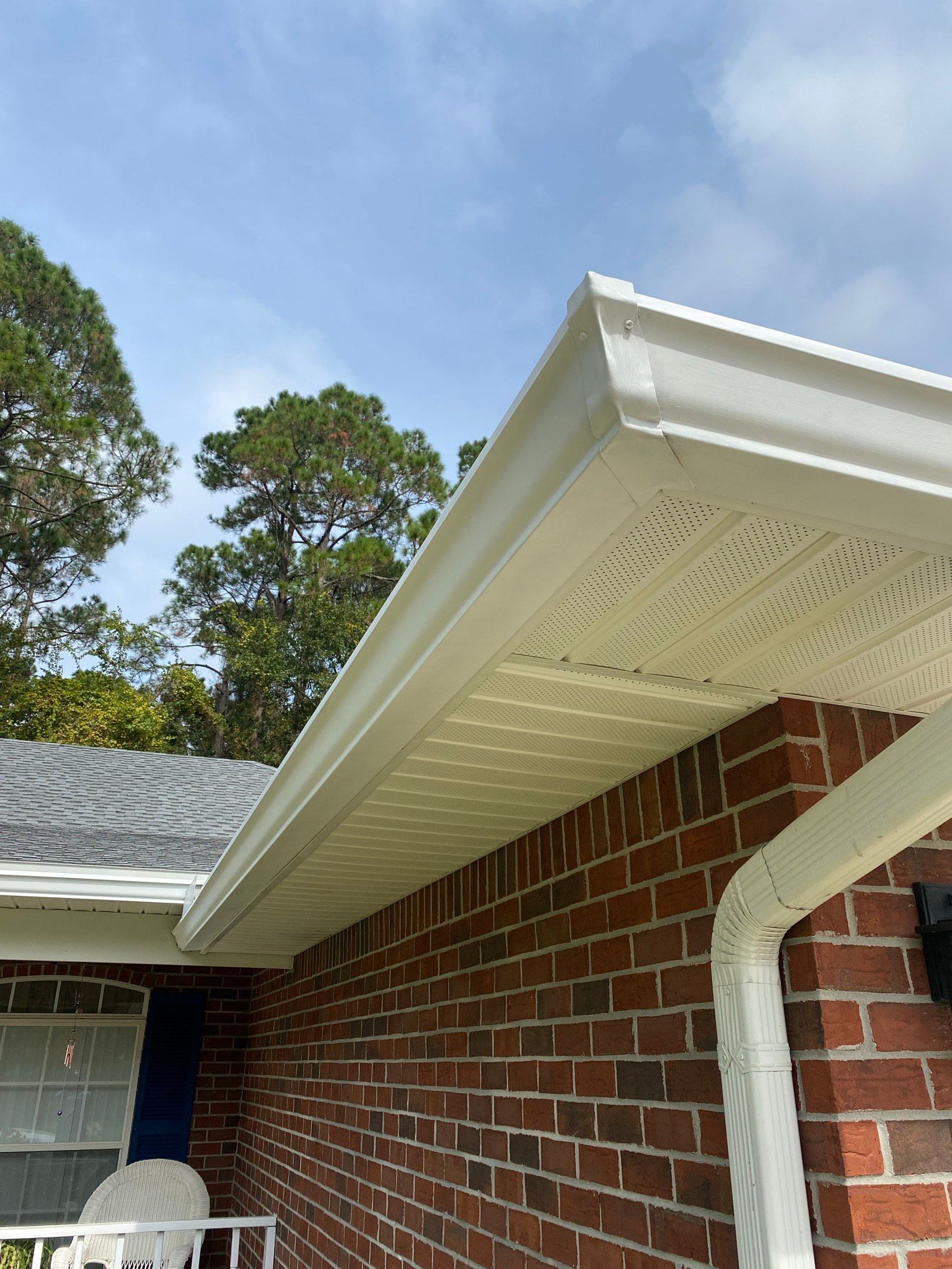 A brick house with a white gutter on the side of it.