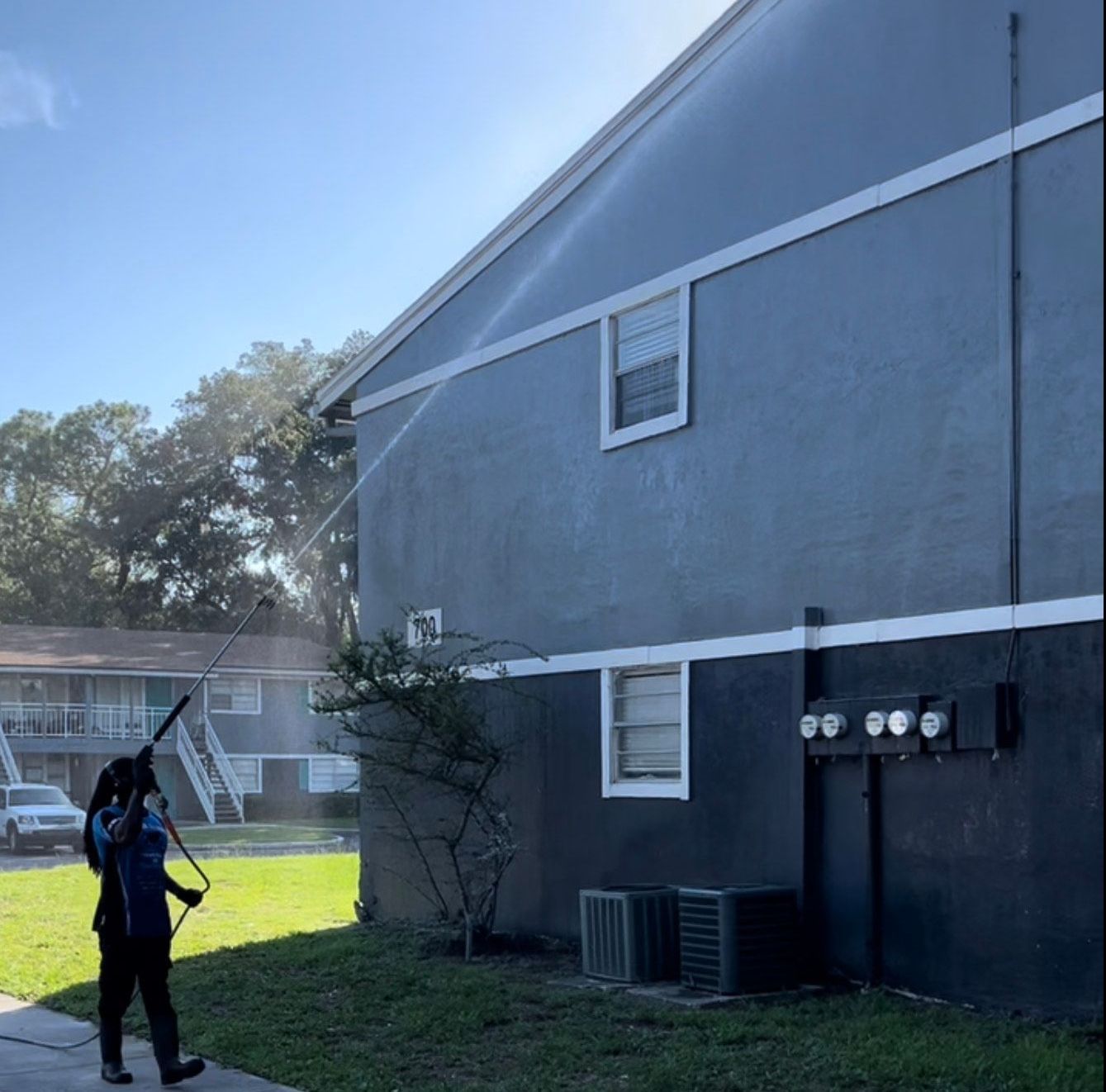 A man is spraying water on the side of a building.