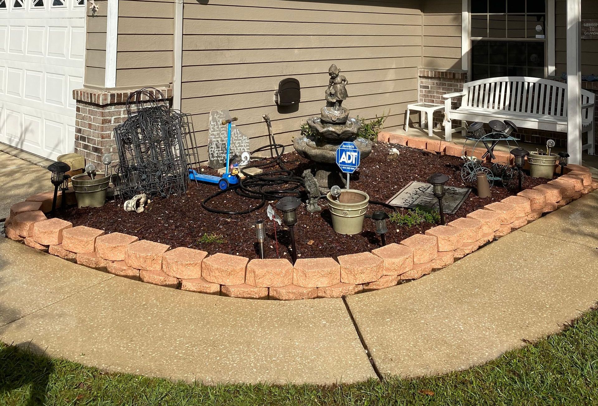 A garden with a fountain in the middle of it in front of a house.