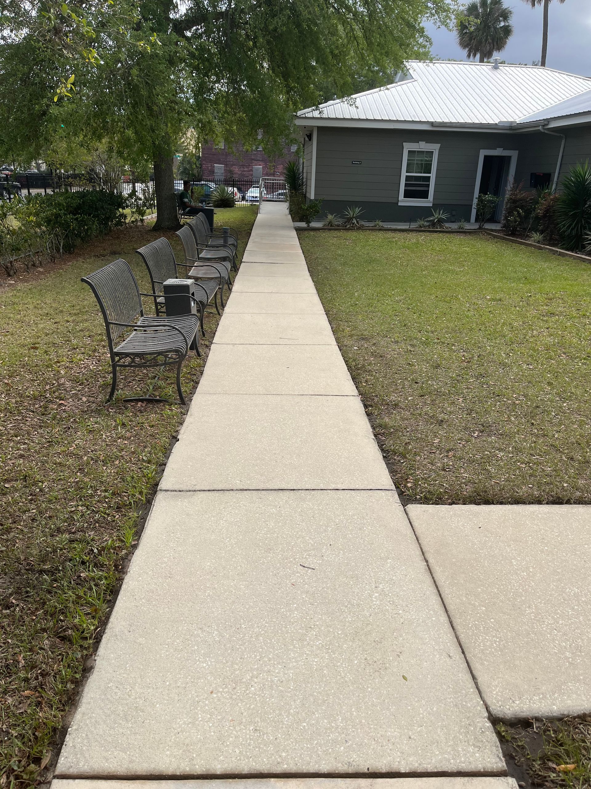 A sidewalk leading to a house with chairs on the side of it.